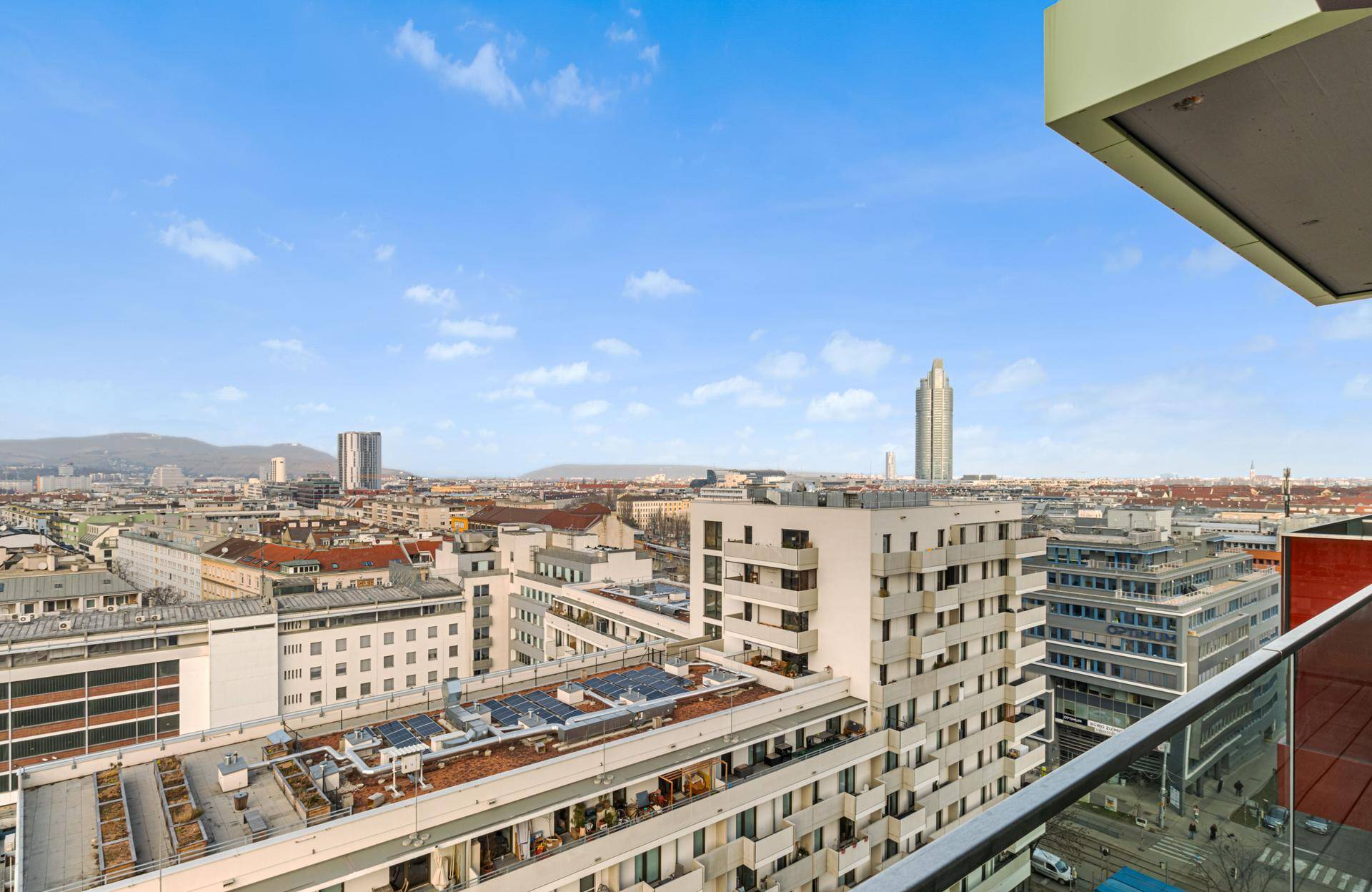 Panoramablick von einem Balkon über die städtische Skyline mit modernen Gebäuden und einem Wolkenkratzer.