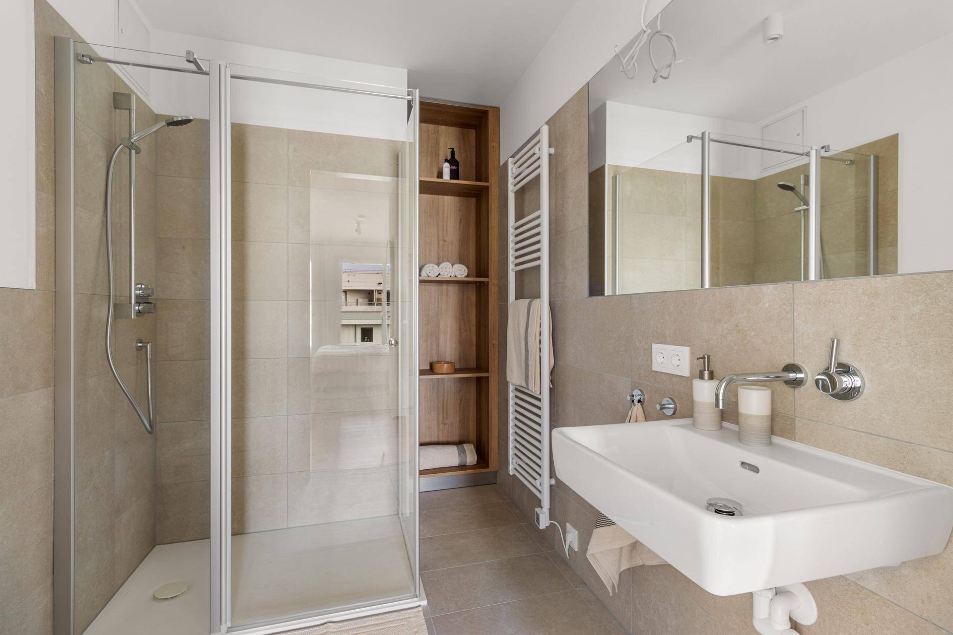 Modernes Badezimmer mit begehbarer Dusche, Einzelwaschbecken und beheiztem Handtuchhalter.