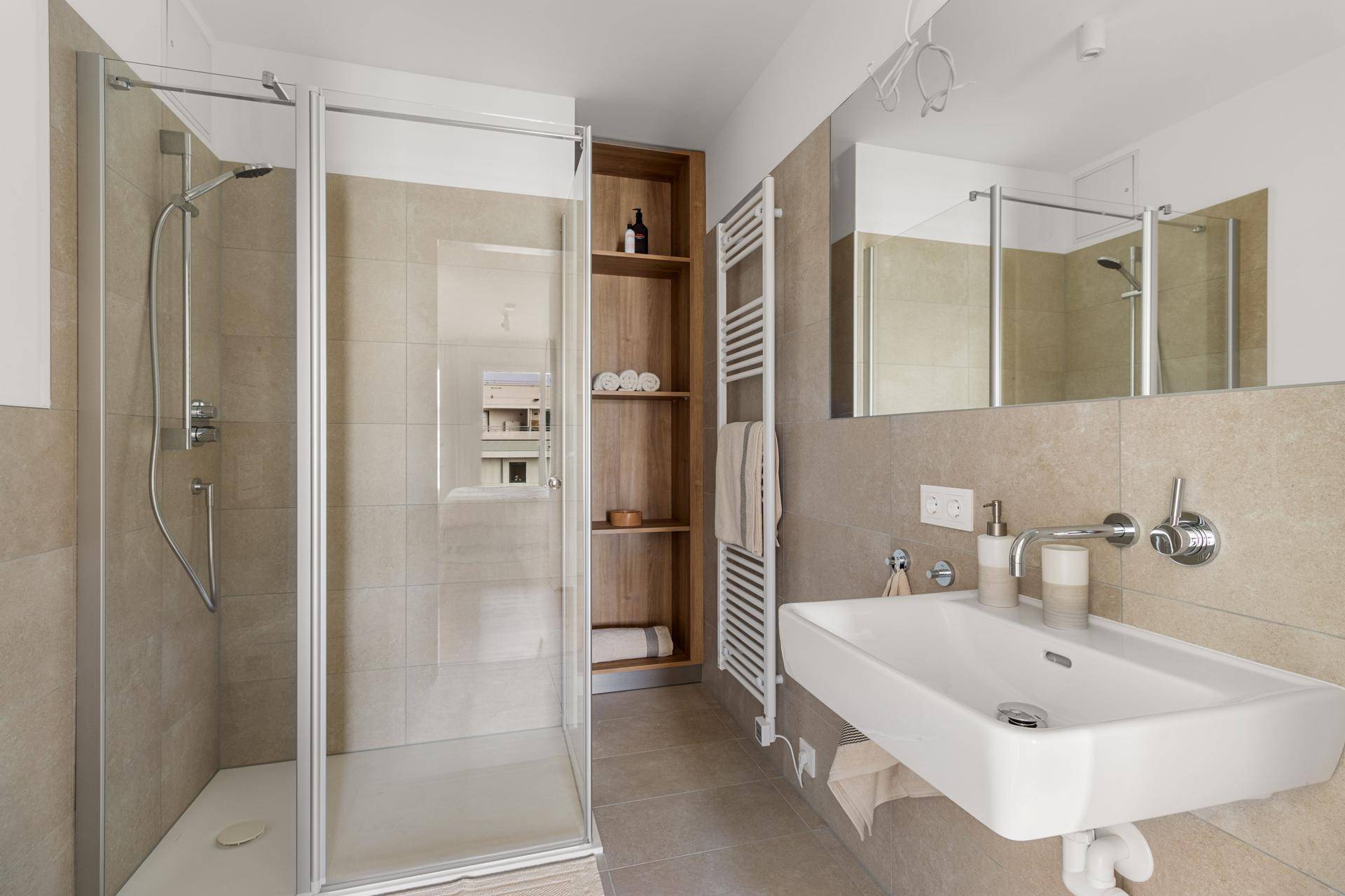 Modernes Badezimmer mit begehbarer Dusche, Einzelwaschbecken und beheiztem Handtuchhalter.