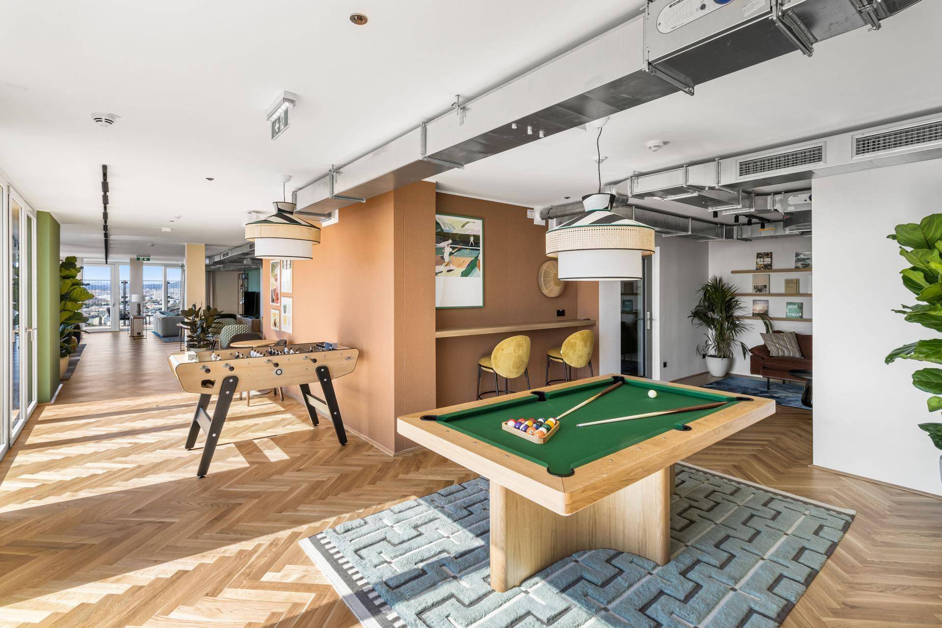 Heller Spielraum mit Billardtisch, Tischfußball und Holzboden.