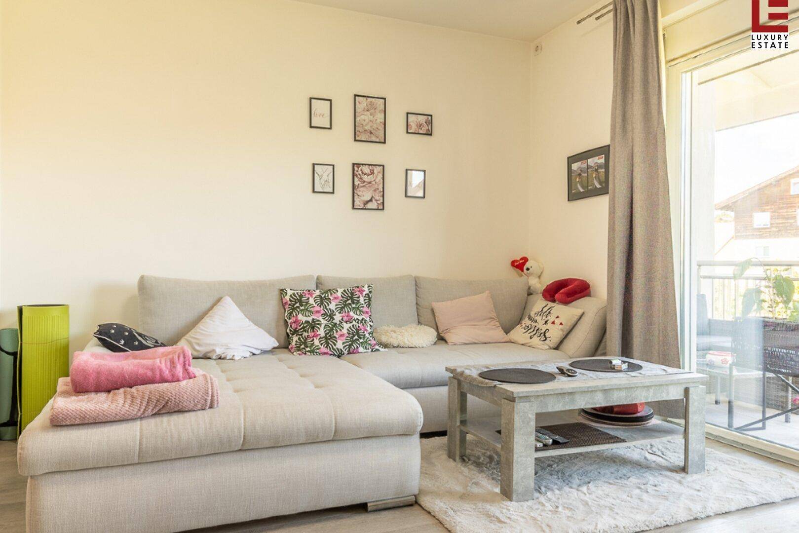Gemütliches Wohnzimmer mit Ecksofa, Couchtisch und Zugang zu einem Balkon.