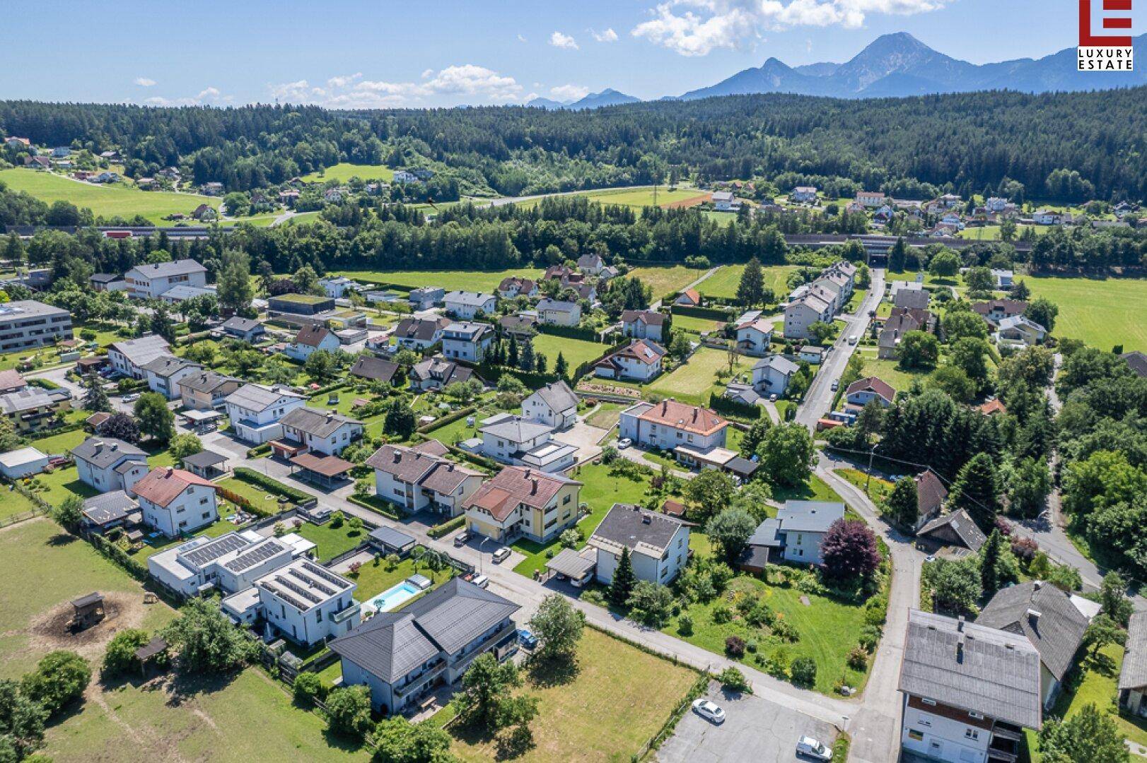 Weitläufige Luftaufnahme einer Wohngegend mit Bergen und Wäldern im Hintergrund.