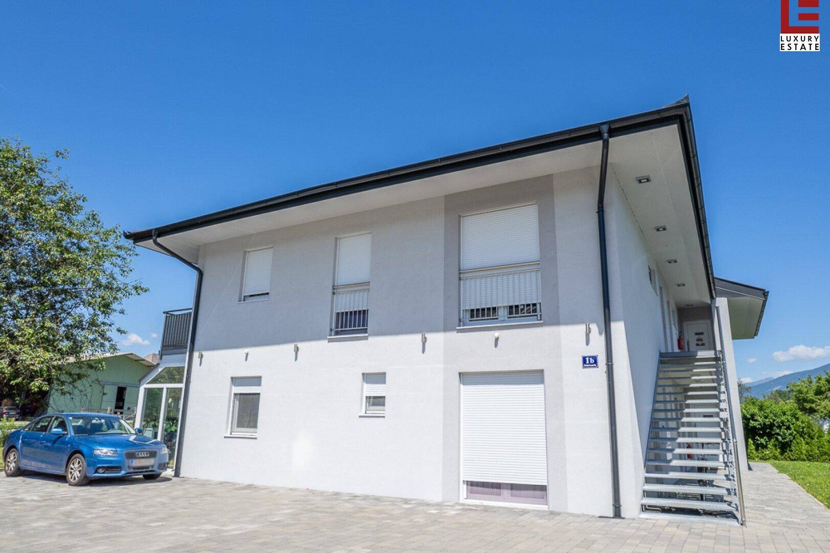 Neubau mit moderner Fassade, Außentreppe und gepflastertem Zugangsbereich.