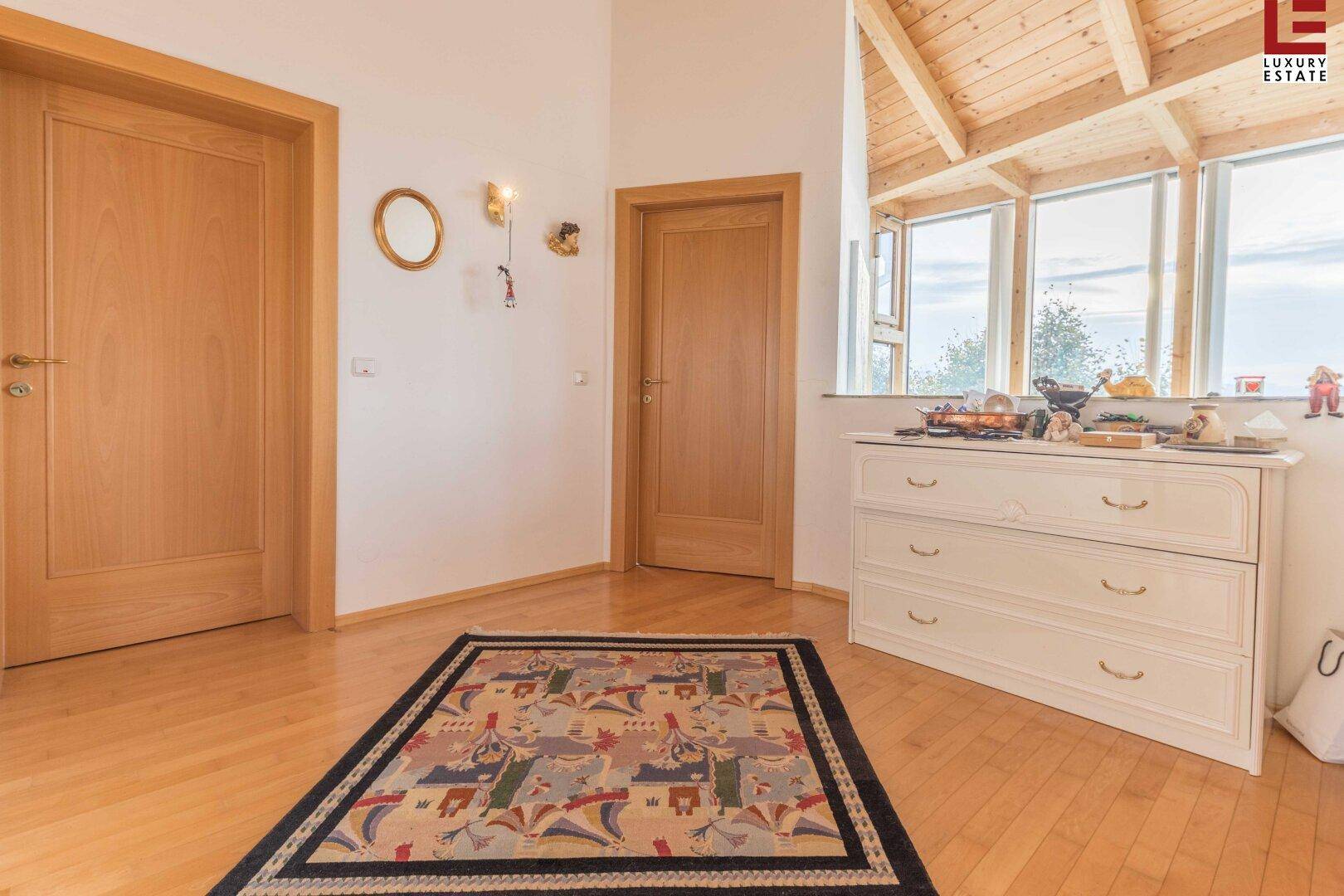 Heller Flurbereich mit Holztüren, Kommode und einer Dachschräge mit Holzverkleidung.