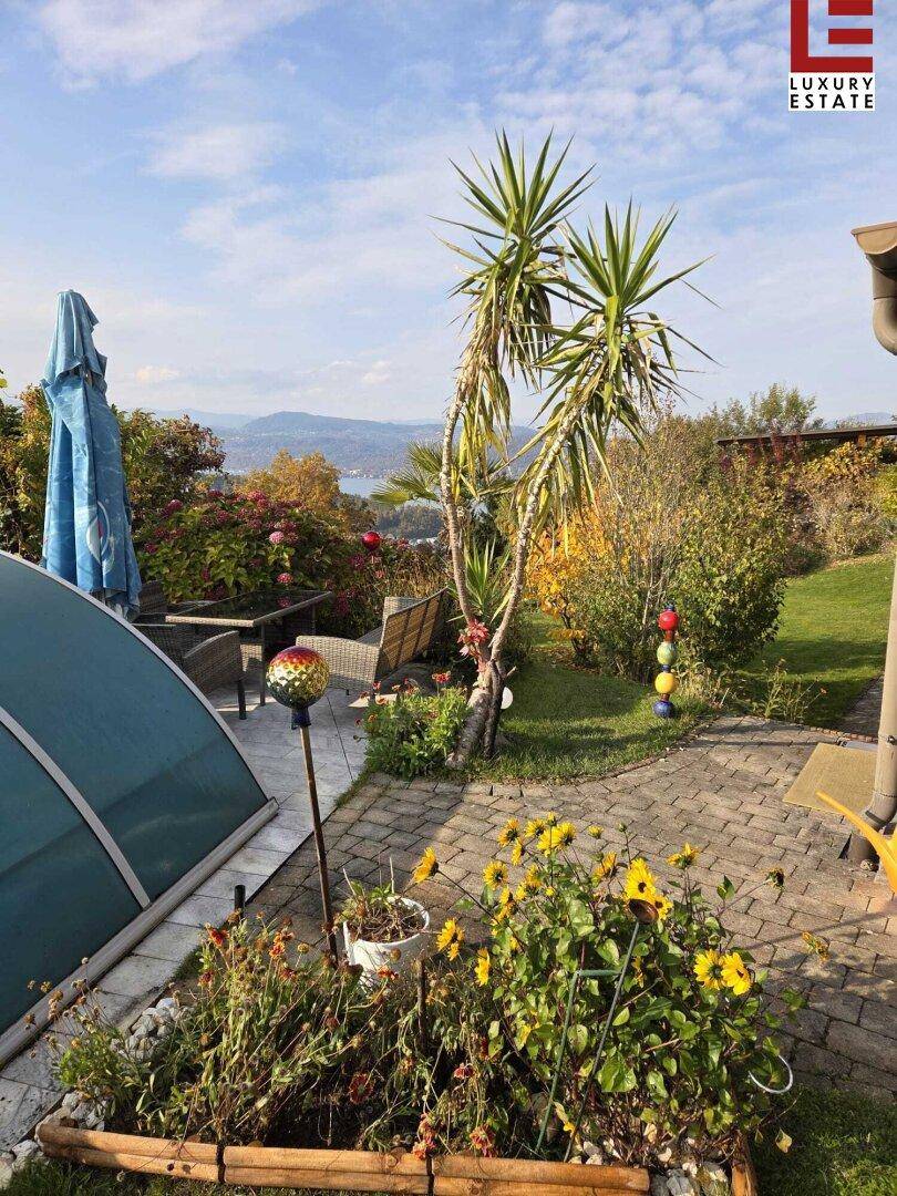 Sonniger Gartenbereich mit überdachtem Pool, Sitzgelegenheiten und herrlichem Seeblick.
