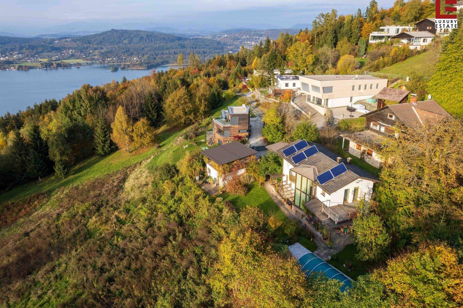 Luftaufnahme von Häusern am Hang mit Blick auf den See und umgeben von Herbstbäumen.