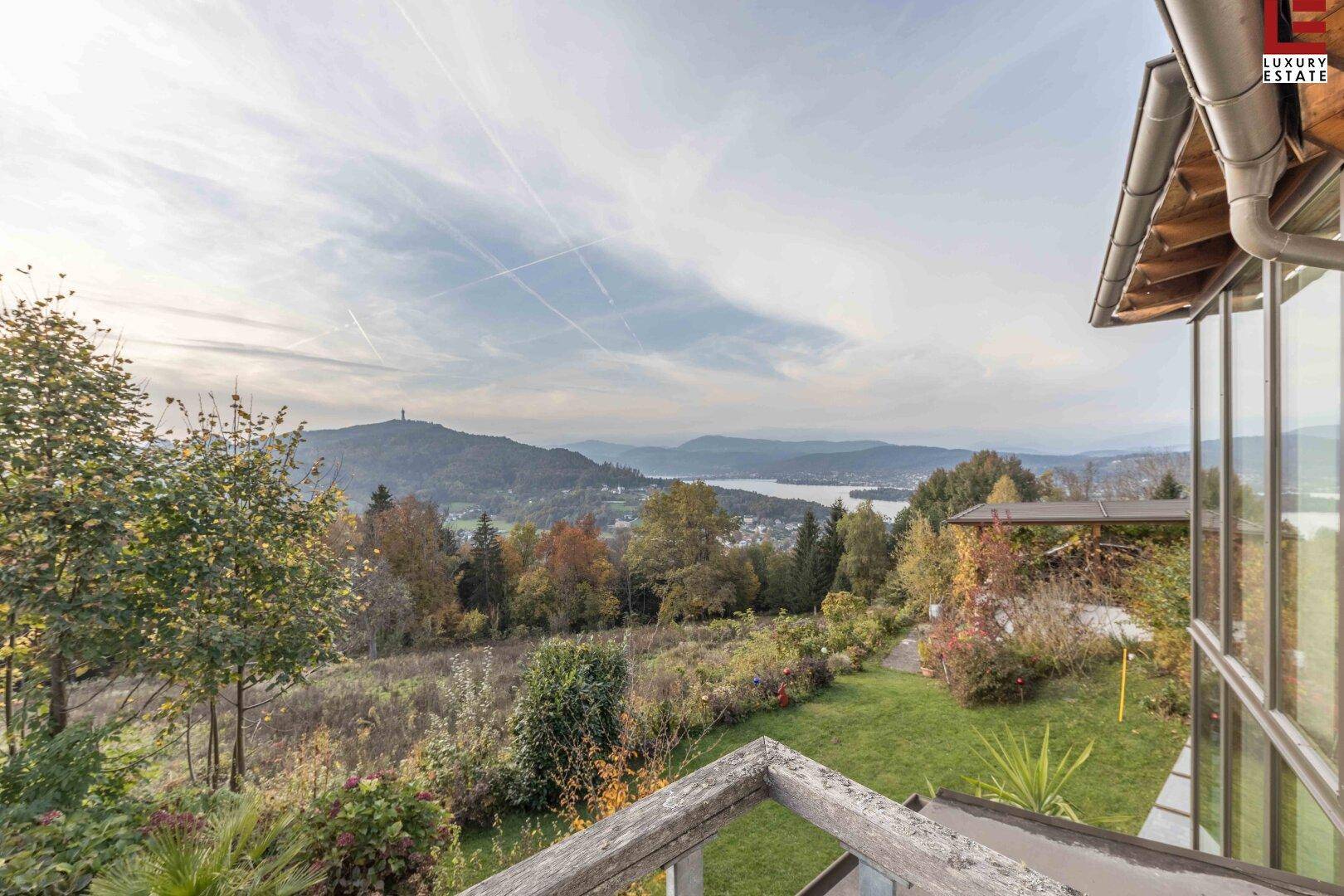 Blick vom Balkon auf die weite Landschaft mit See, Bergen und herbstlicher Vegetation.