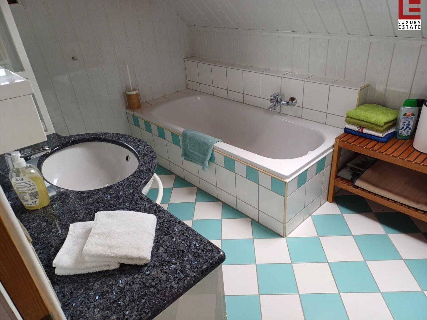 Badezimmer mit Badewanne, Granitwaschtisch und auffälligem blau-weißem Fliesenboden.