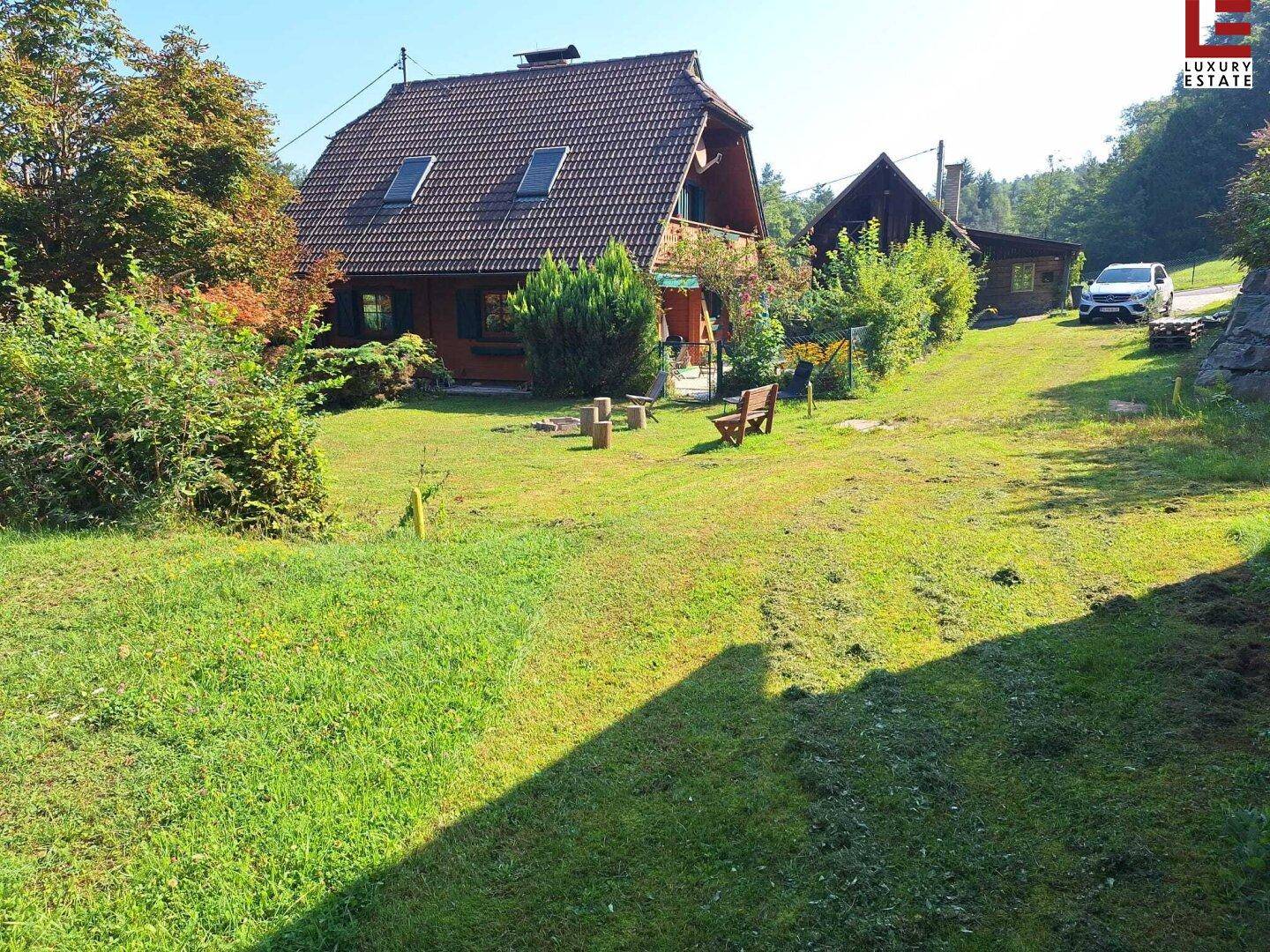 Weitläufiges Grundstück mit Rasenfläche, Holzhaus und Zufahrt.
