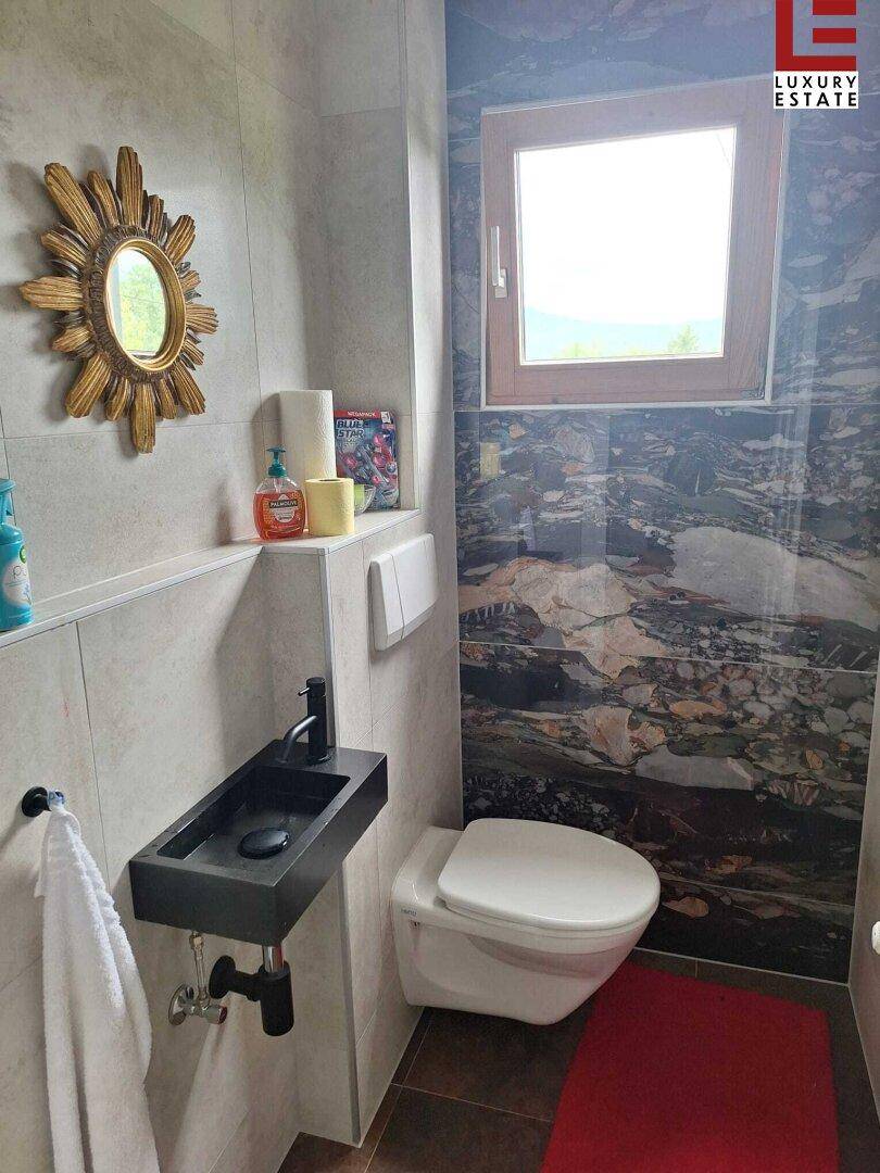 Modernes Gäste-WC mit Wand-WC, kleinem Waschbecken und Fenster.