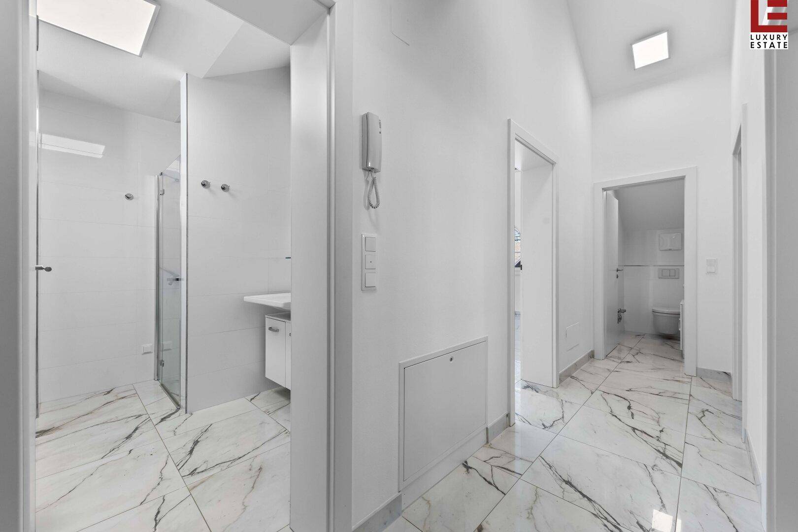 Heller Flur mit eleganten Marmorfliesen, der zu den modernen Badezimmern führt.