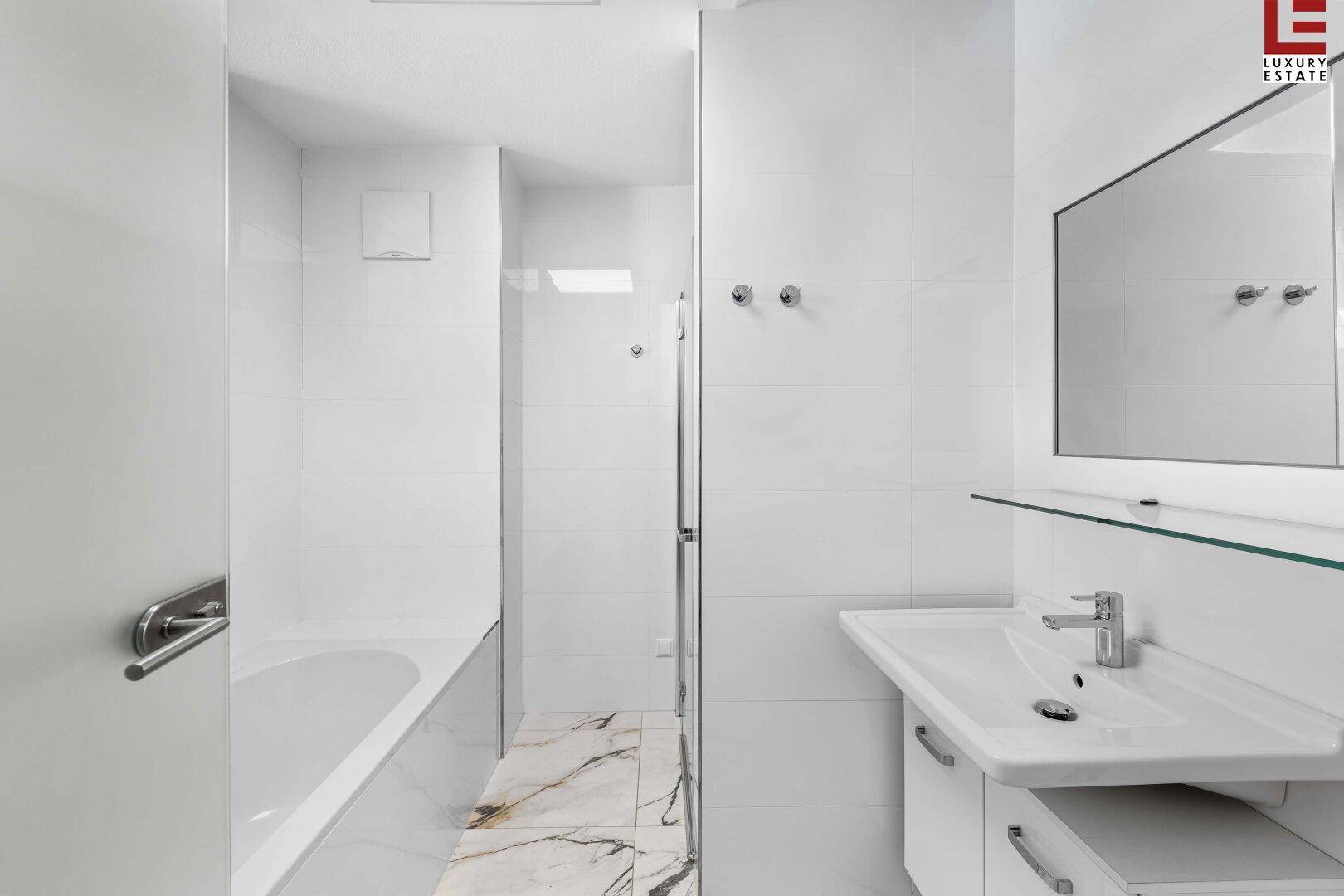 Modernes Badezimmer mit Badewanne, Dusche und stilvollen Marmorfliesen.