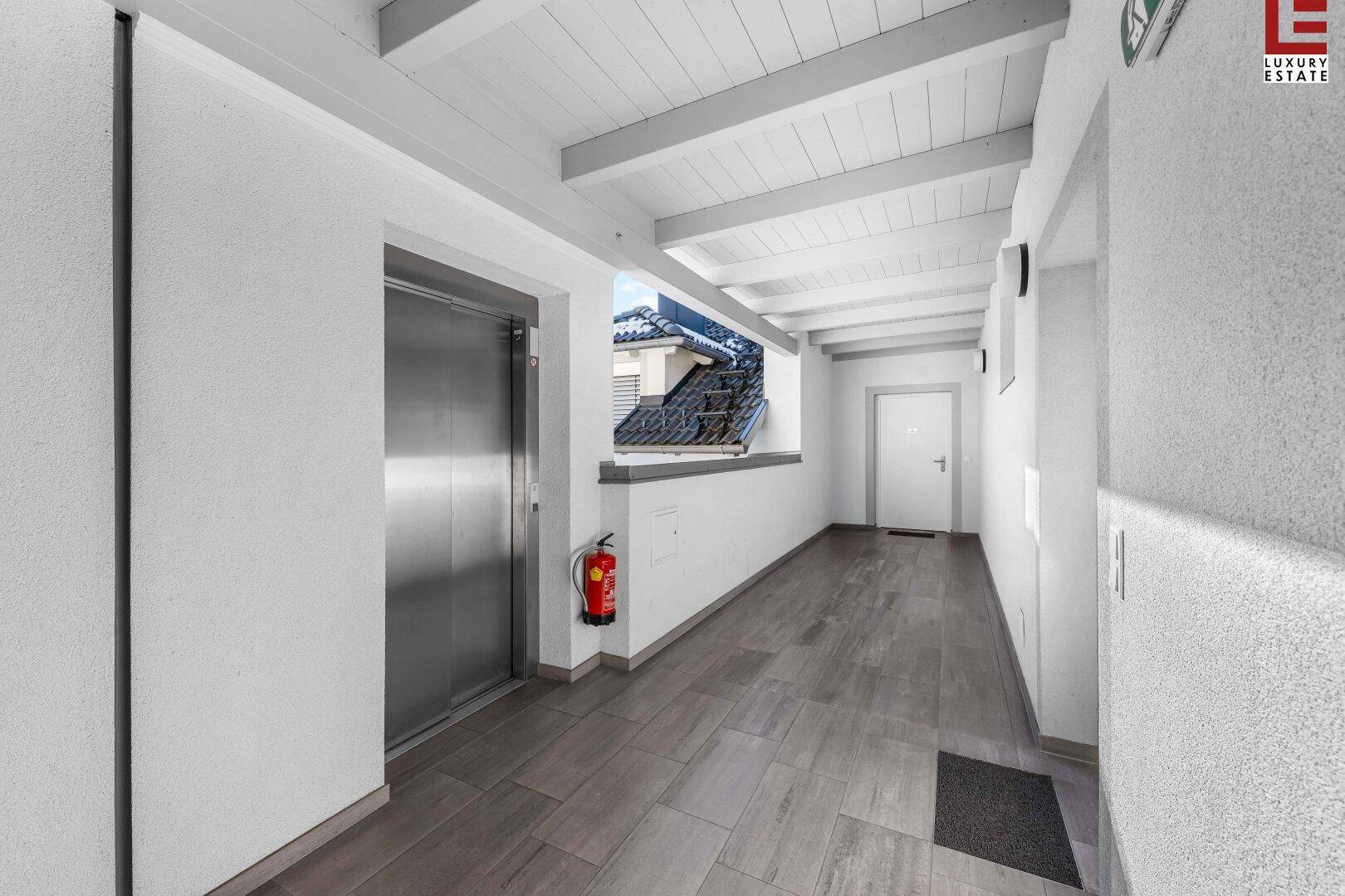 Heller Flur mit Holzbalkendecke und einem modernen Aufzug für bequemen Zugang.