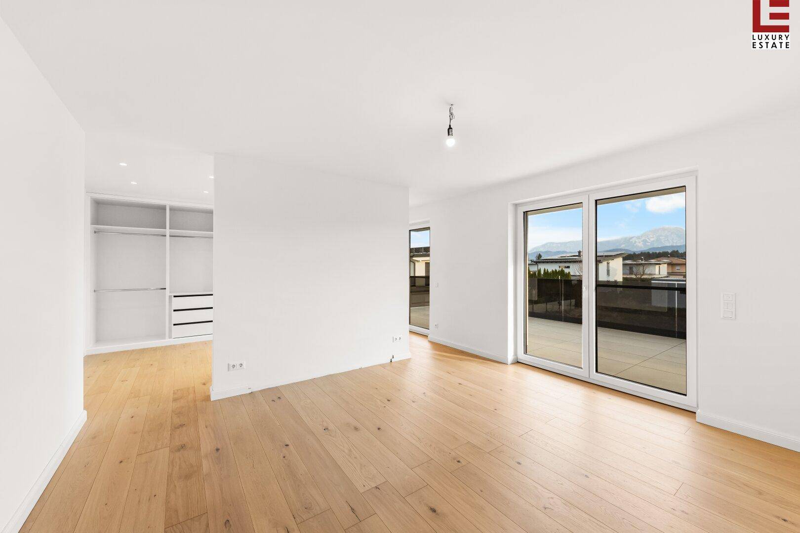 Geräumiges Schlafzimmer mit Holzboden, Einbauschränken und Zugang zu einer Terrasse mit Bergblick.