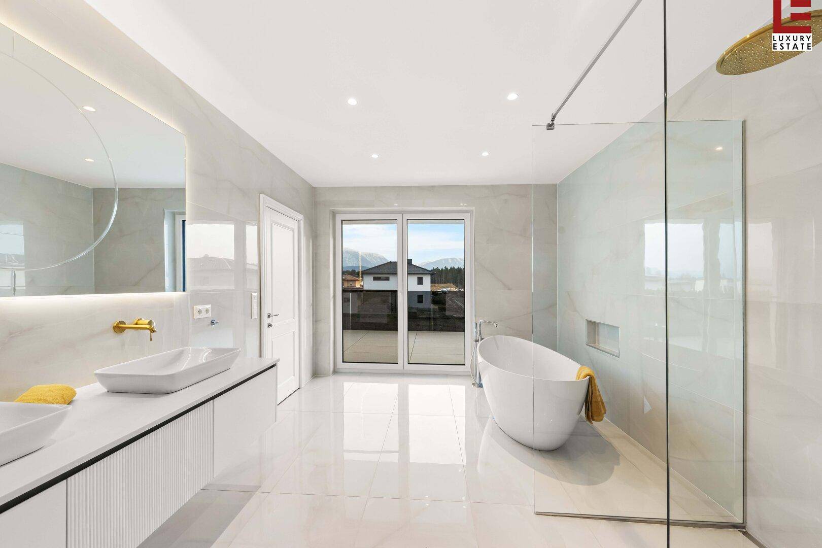 Luxuriöses Badezimmer mit freistehender Badewanne, großer Dusche und Blick auf die Berge.