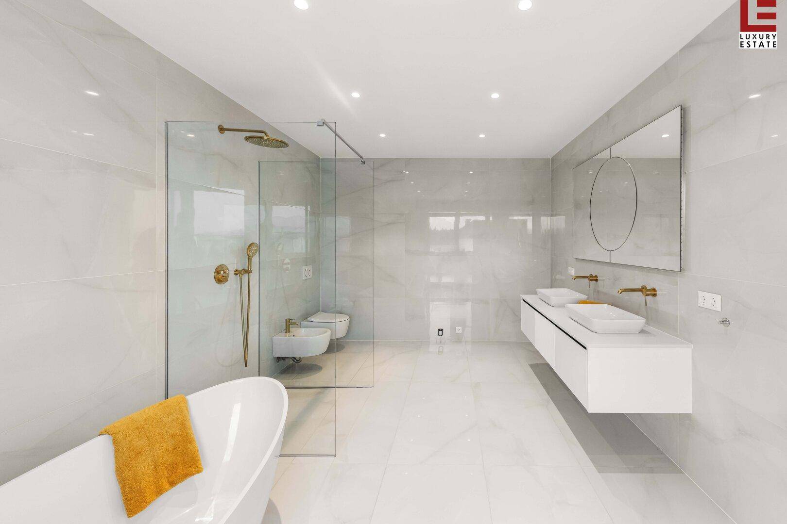 Elegantes Badezimmer mit freistehender Badewanne, Bidet und Doppelwaschbecken in modernem Design.