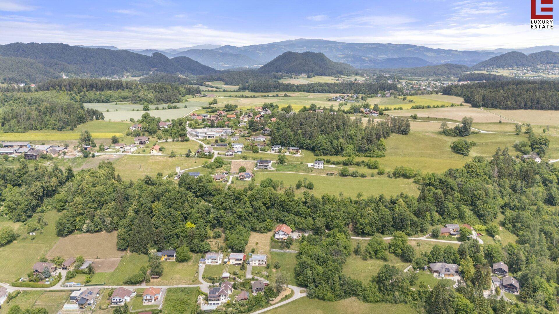 Weitläufige Luftaufnahme einer idyllischen ländlichen Gegend mit verstreuten Häusern und grünen Feldern.