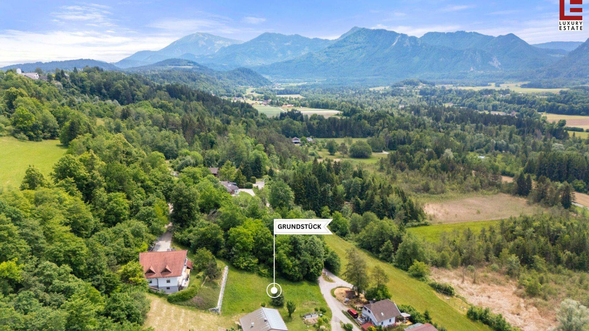 Luftaufnahme eines Grundstücks in ländlicher Umgebung mit malerischem Bergblick und viel Grün.