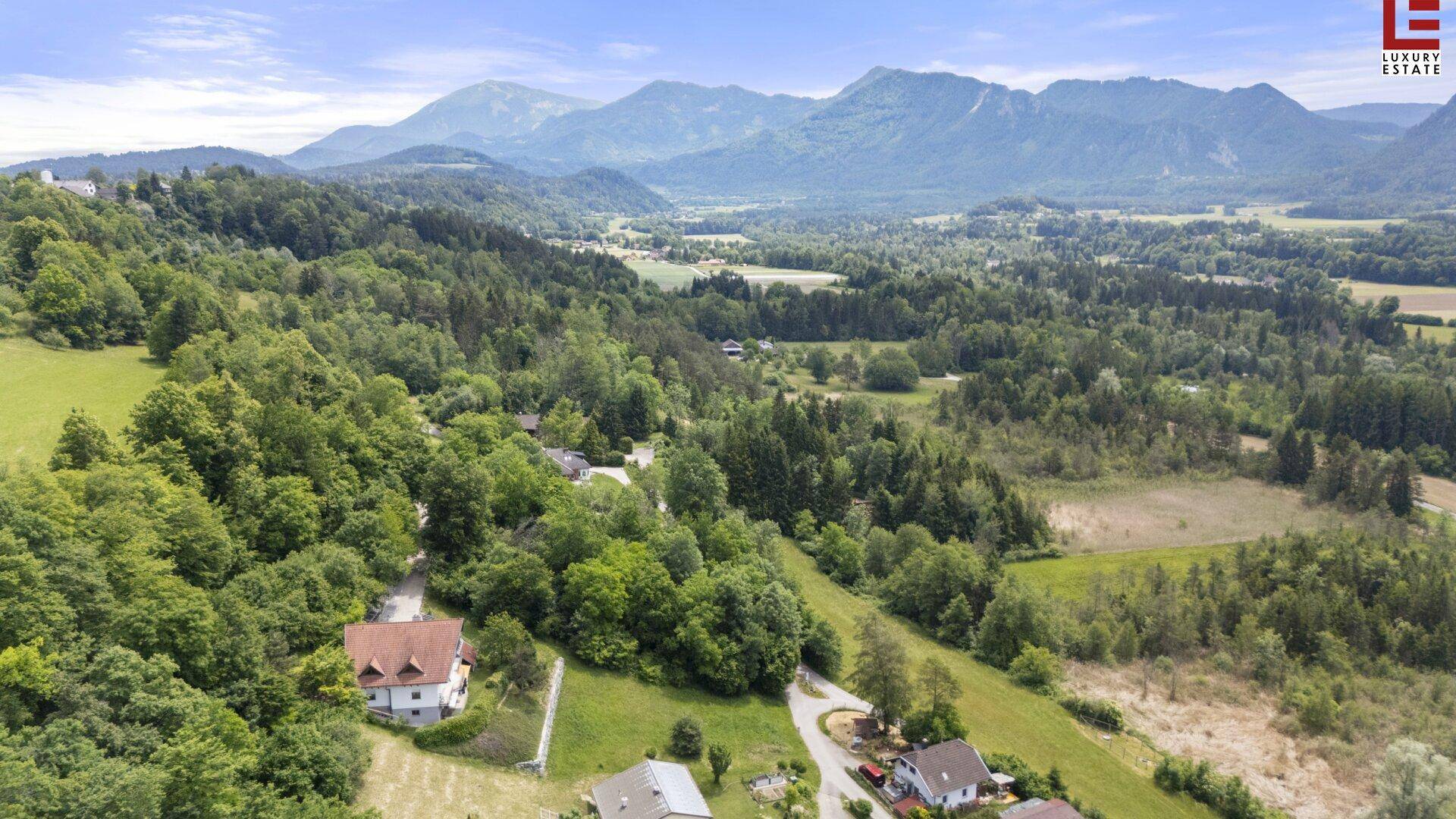 Luftaufnahme eines Grundstücks in ländlicher Umgebung mit malerischem Bergblick und viel Grün.