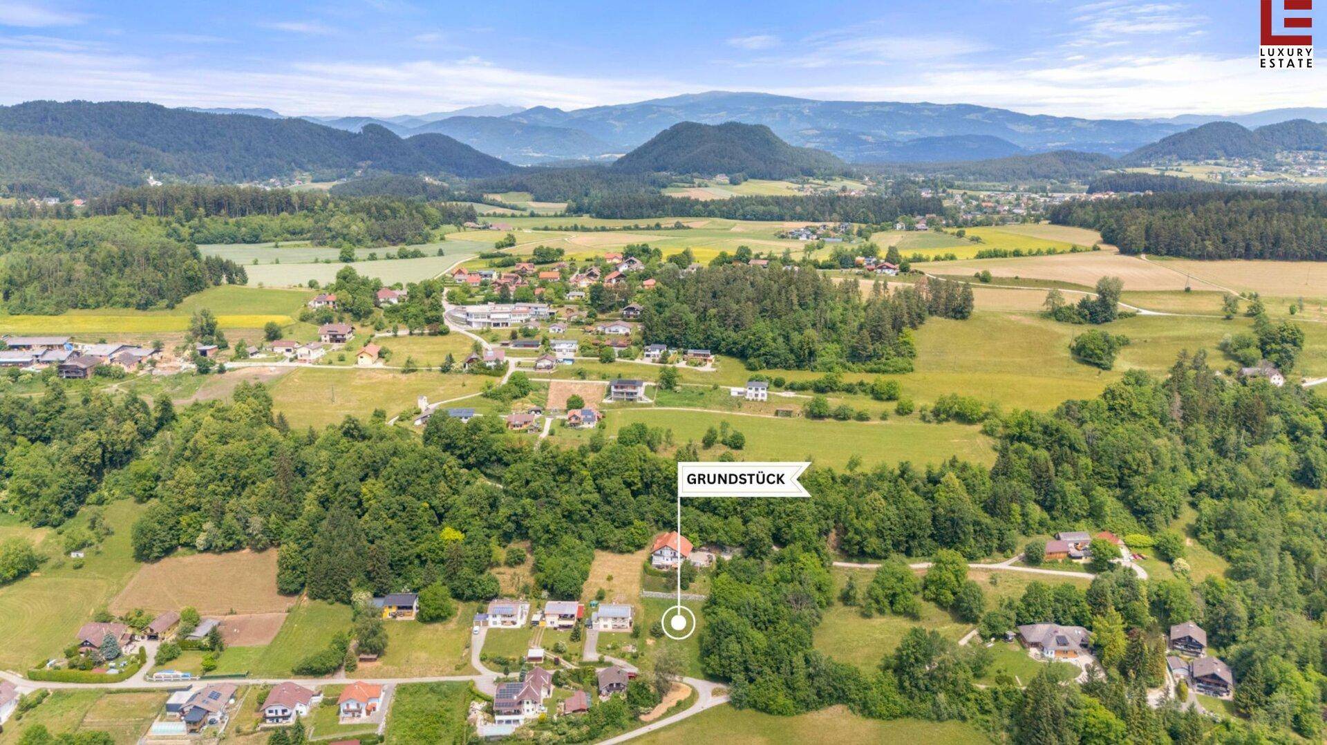 Weitläufige Luftaufnahme einer idyllischen ländlichen Gegend mit verstreuten Häusern und grünen Feldern.