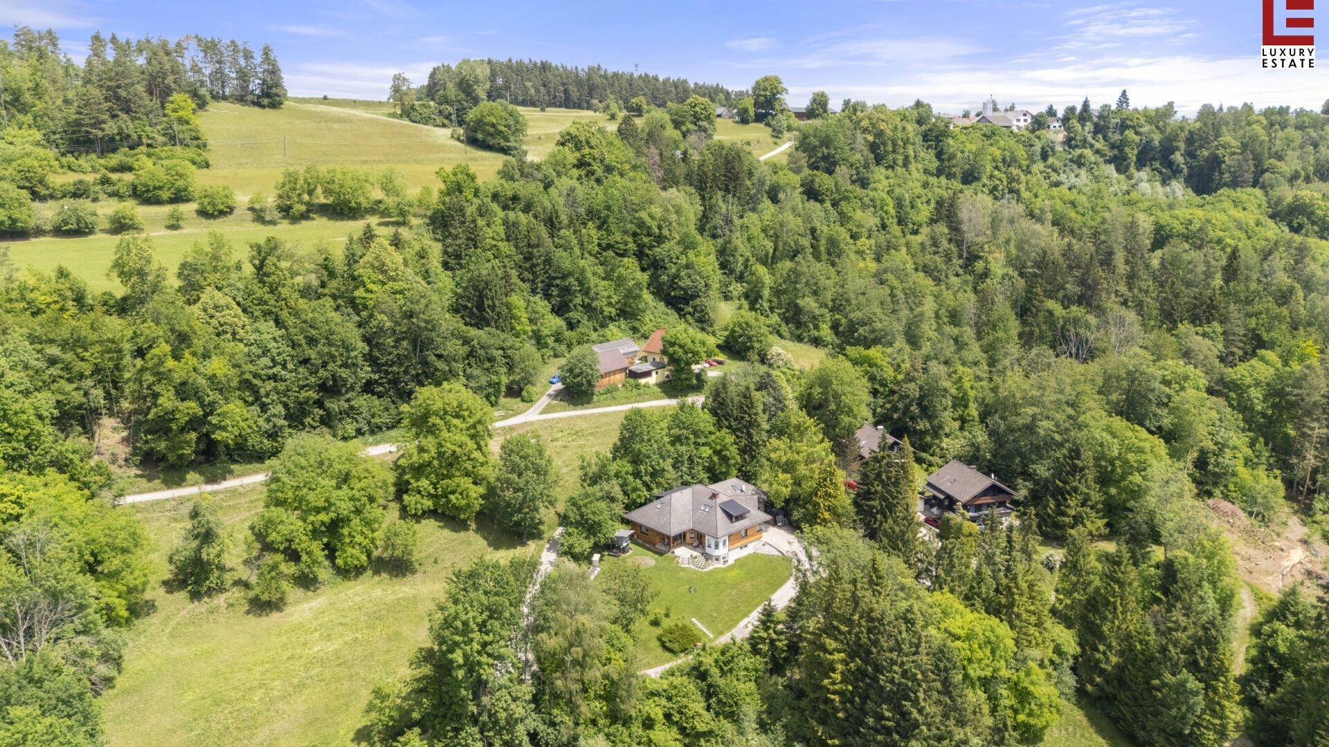 Luftaufnahme des Anwesens, eingebettet in eine grüne Hügellandschaft mit weiteren Häusern.