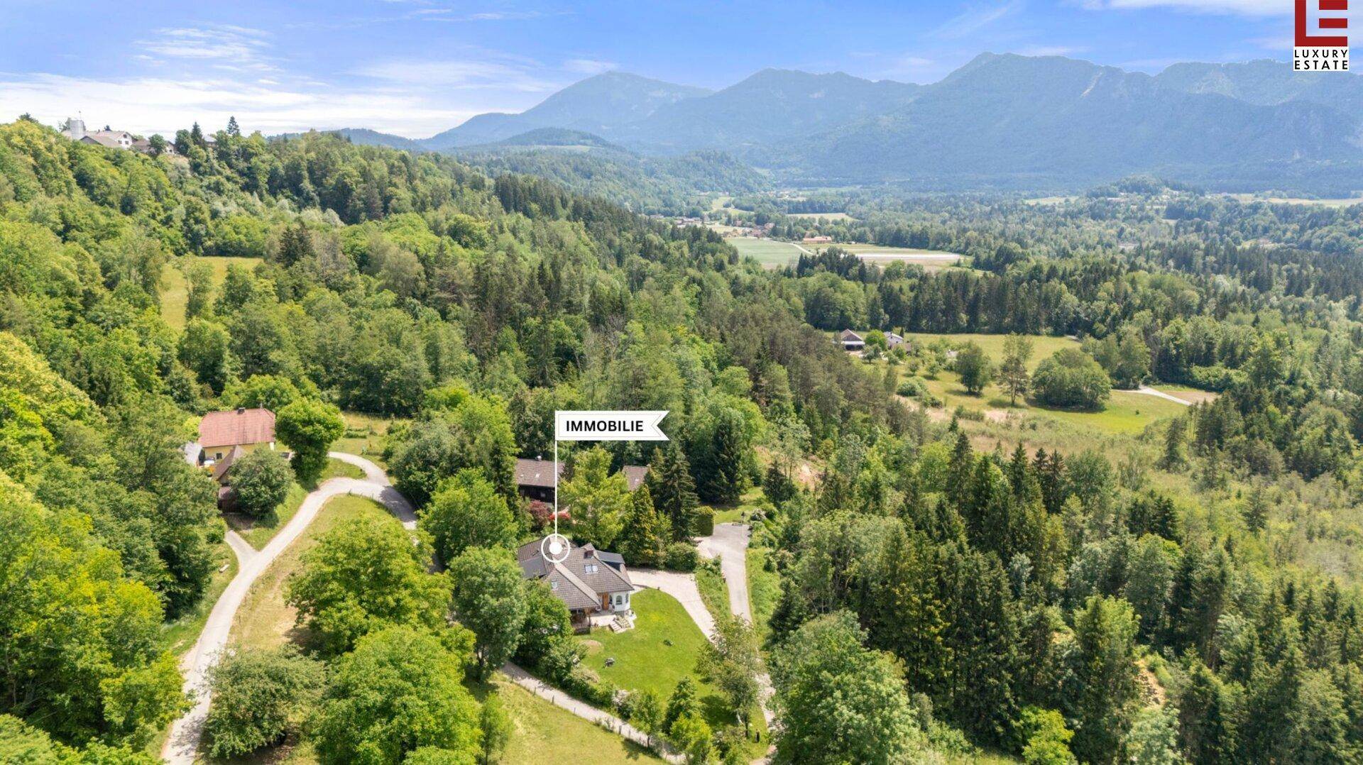 Luftaufnahme des Anwesens, markiert als Immobilie, umgeben von Wäldern und Bergen.