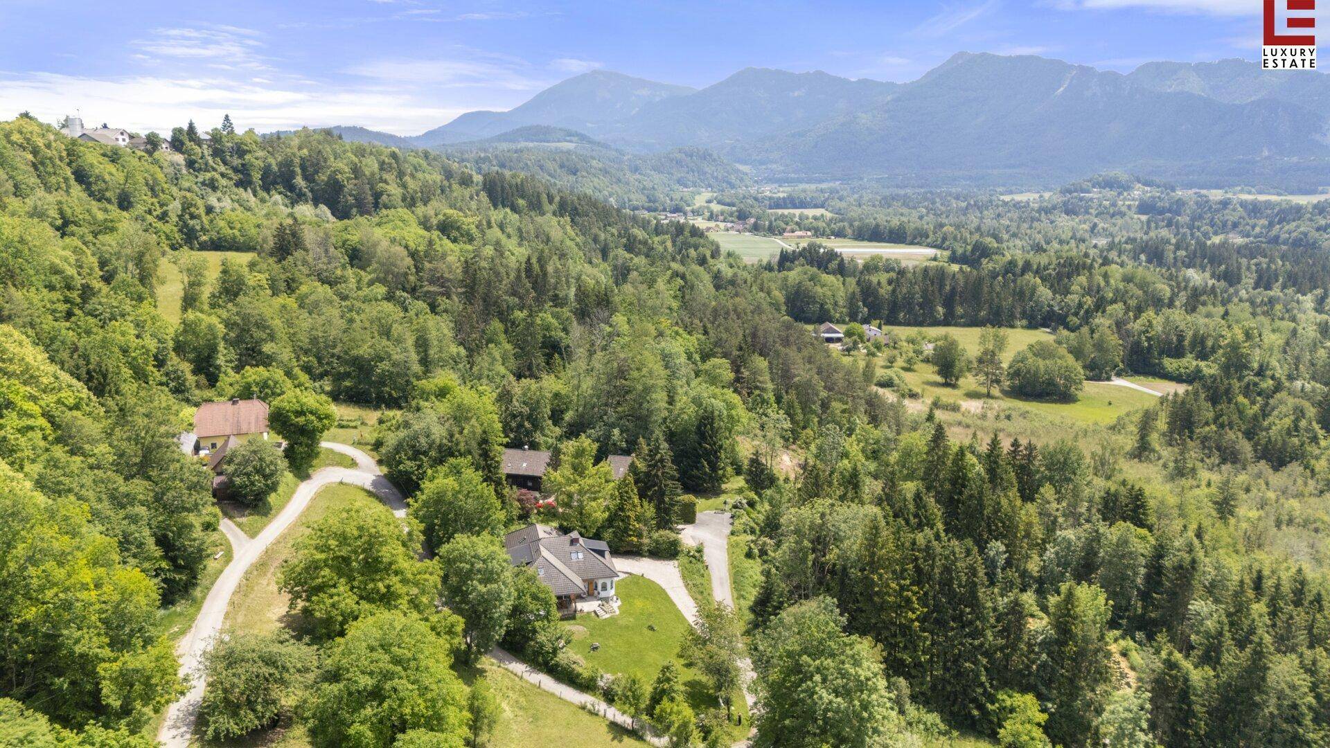 Luftaufnahme des Anwesens, eingebettet in eine grüne Hügellandschaft mit weiteren Häusern.