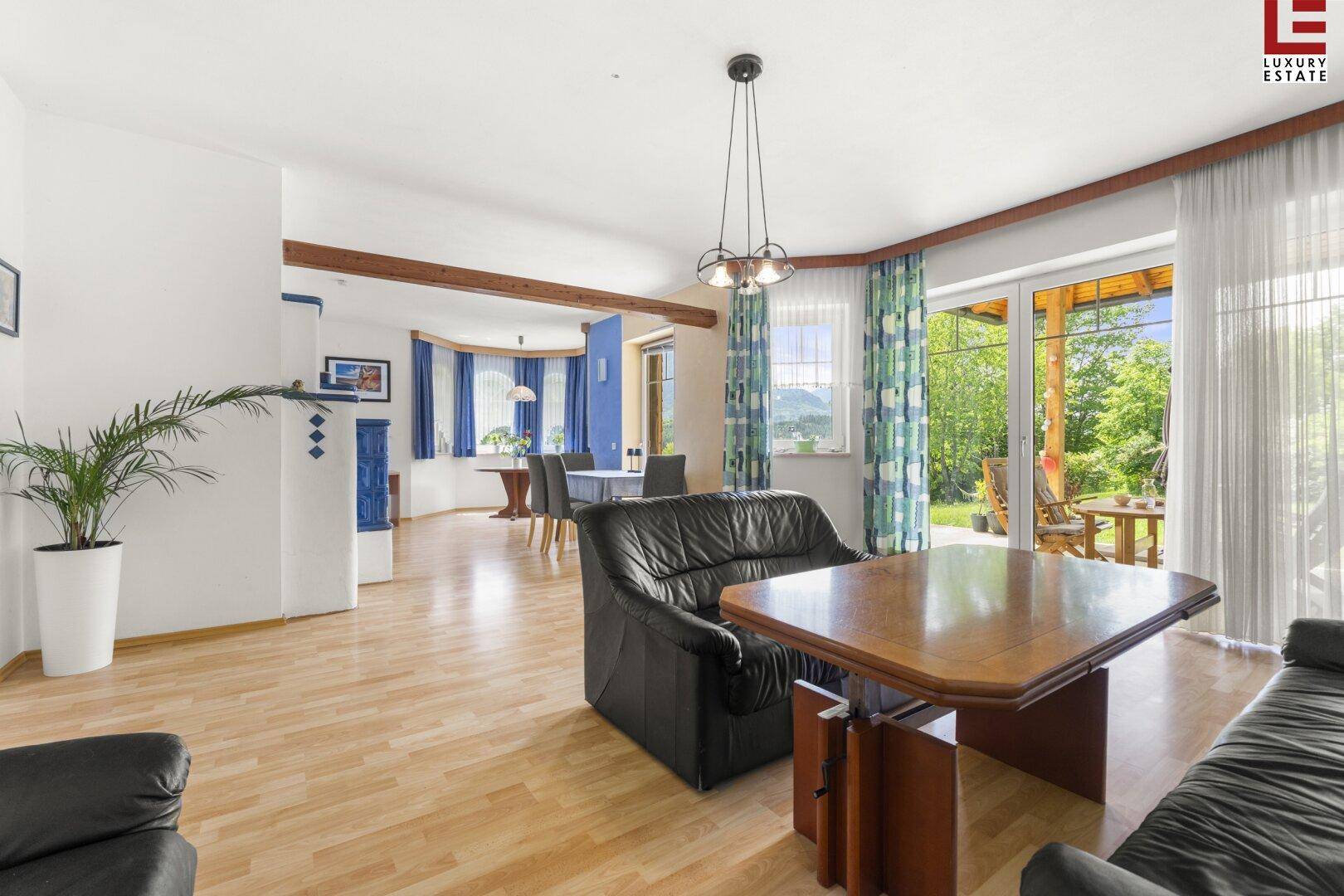 Geräumiger Wohn-Essbereich mit Holzboden, Kachelofen und Zugang zur Terrasse.