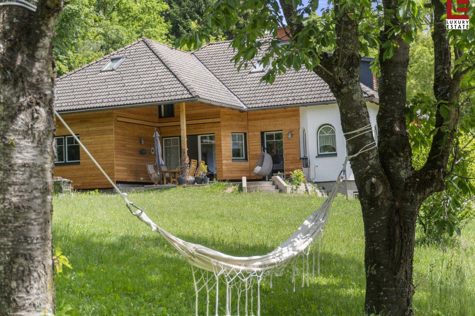 Idyllischer Gartenbereich mit Hängematte und Blick auf die Holzfassade des Hauses.