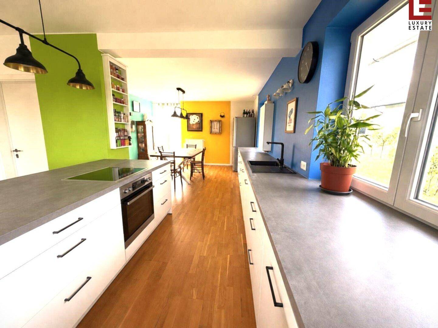 Offener Wohn- und Essbereich mit moderner Küche, Holzboden und farbenfrohen Wänden.
