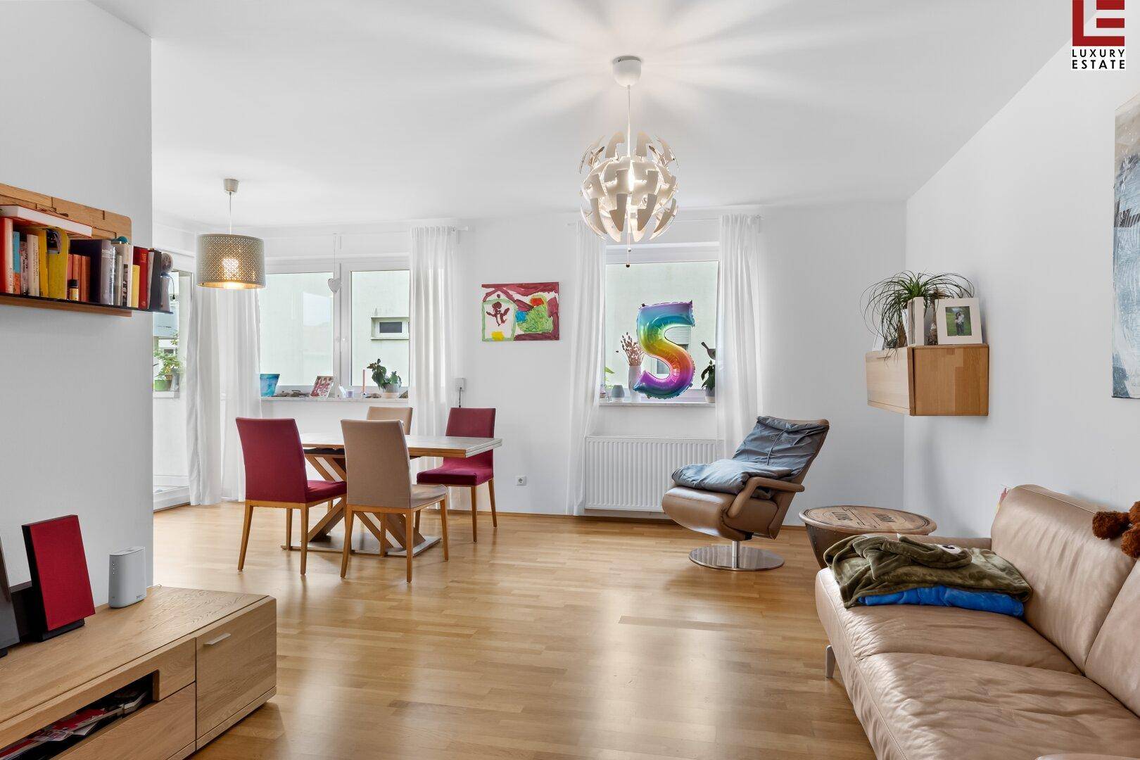 Großzügiger Wohn-Essbereich mit Holzboden, bequemer Couch und viel Tageslicht.