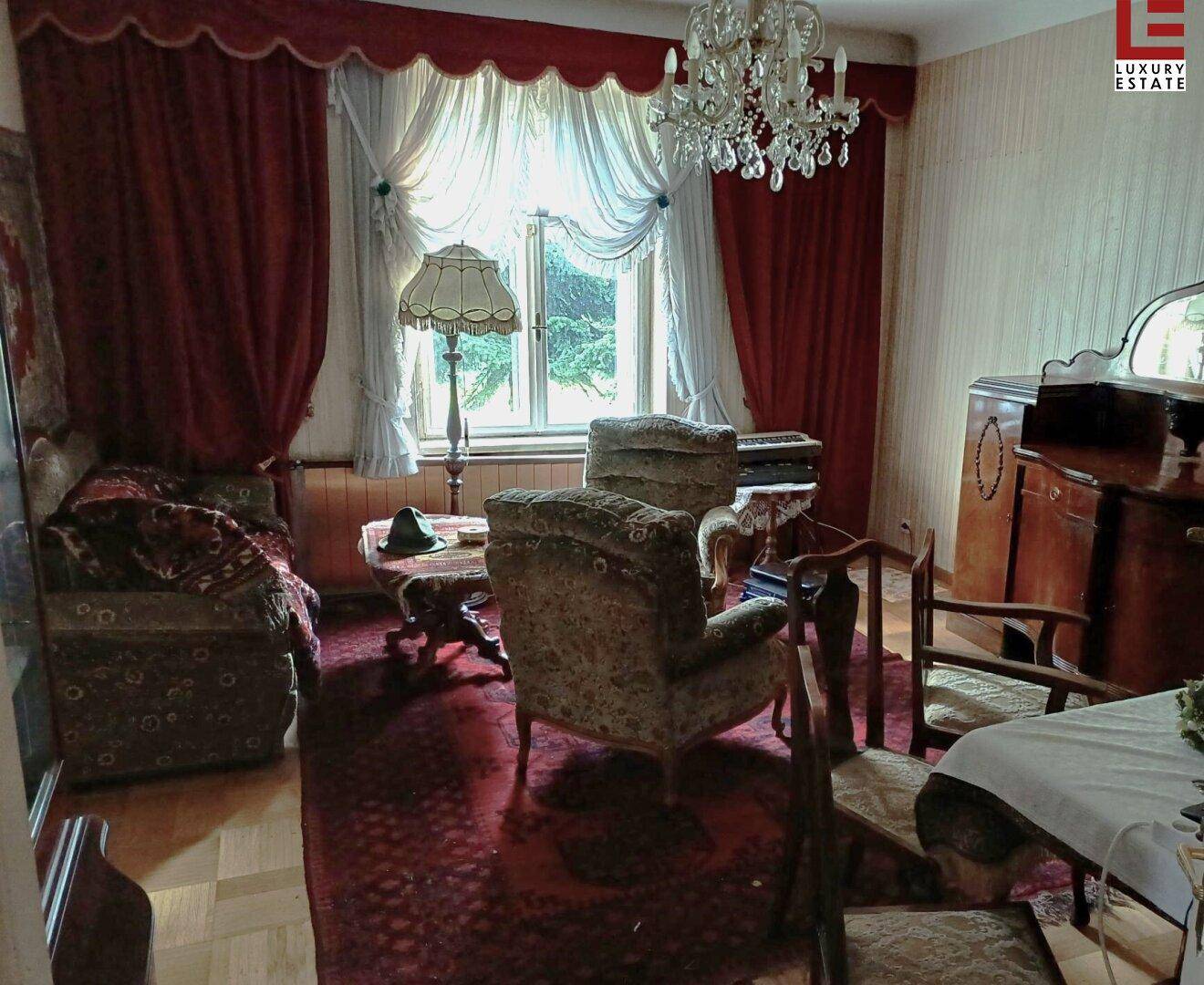 Helles Wohnzimmer mit Kronleuchter, Parkettboden und Blick in den Garten.