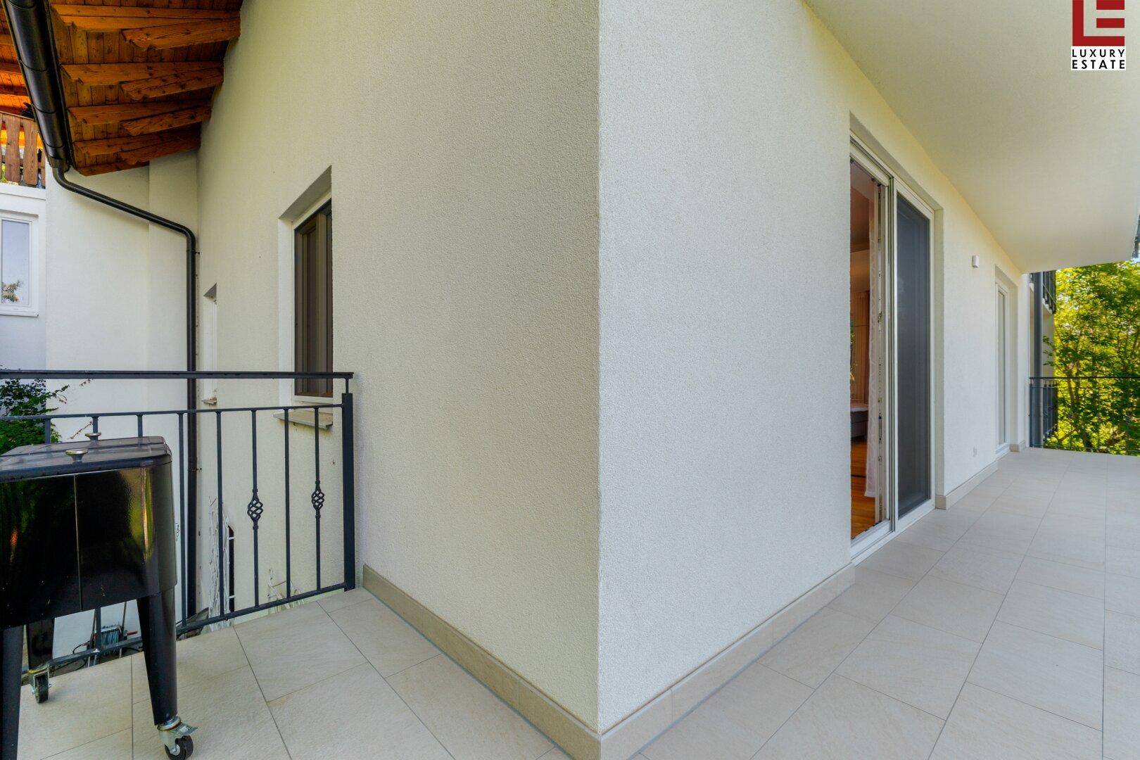 Langer Balkon mit Fliesenboden und Blick auf die grüne Umgebung, ideal für Entspannung im Freien.