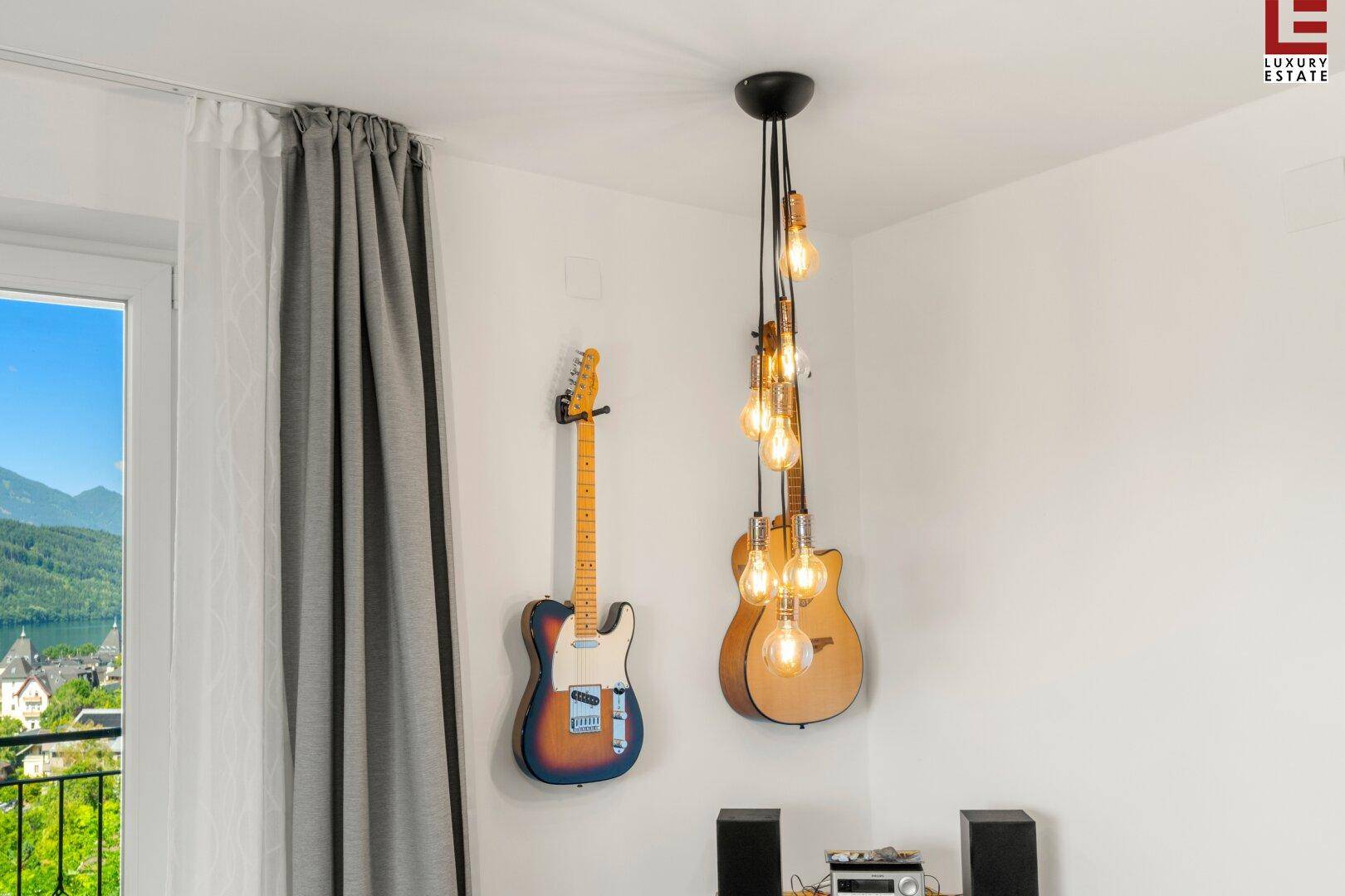 Wanddekoration mit Gitarren und einer einzigartigen Deckenleuchte, die einen musikalischen Akzent setzt.