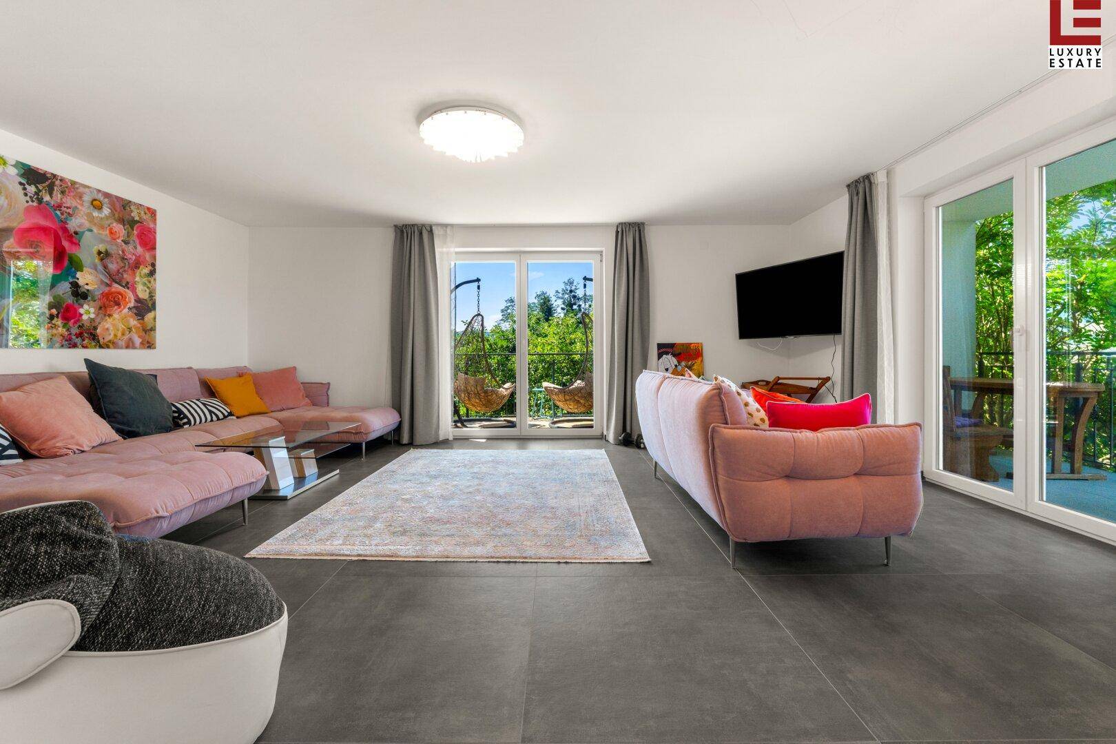 Helles Wohnzimmer mit modernen Sofas, großformatigen Fliesen und Zugang zum Balkon mit Aussicht.