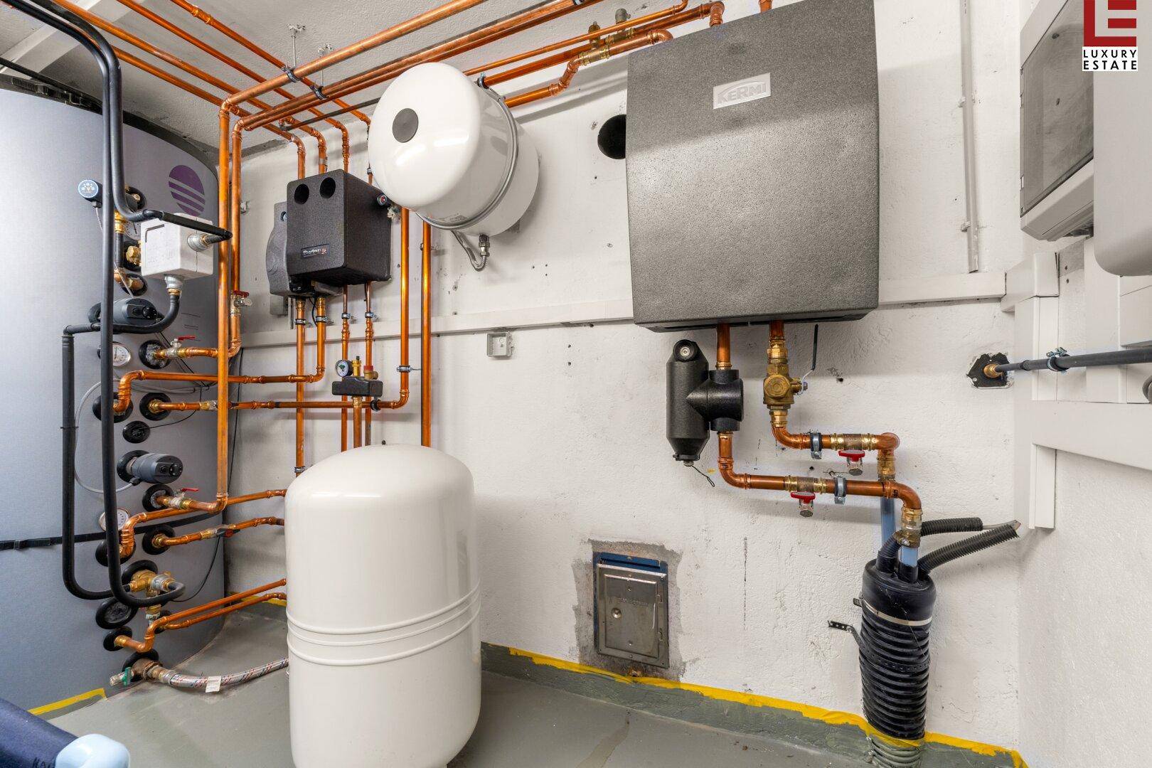 Technikraum mit Heizungsanlage und Warmwasserspeicher, gut organisiert und funktional.