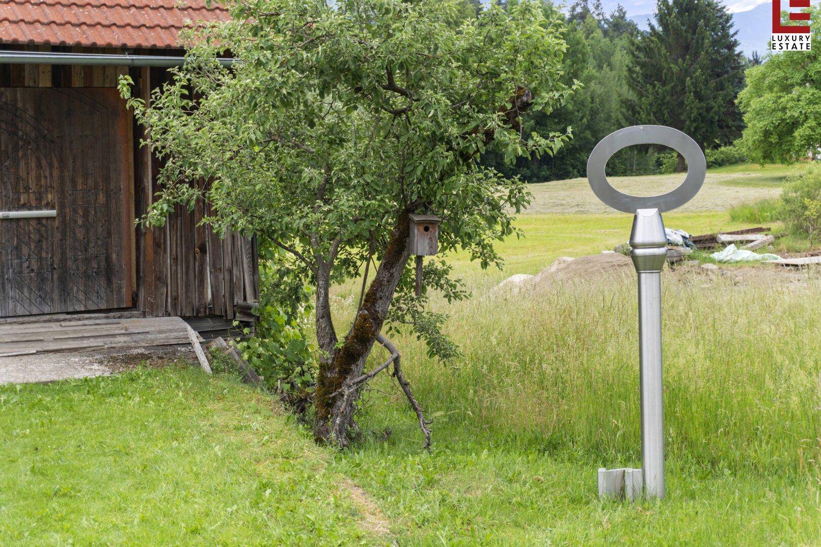 Grüner Gartenbereich mit einem dekorativen Schlüssel-Kunstwerk und einem Obstbaum.