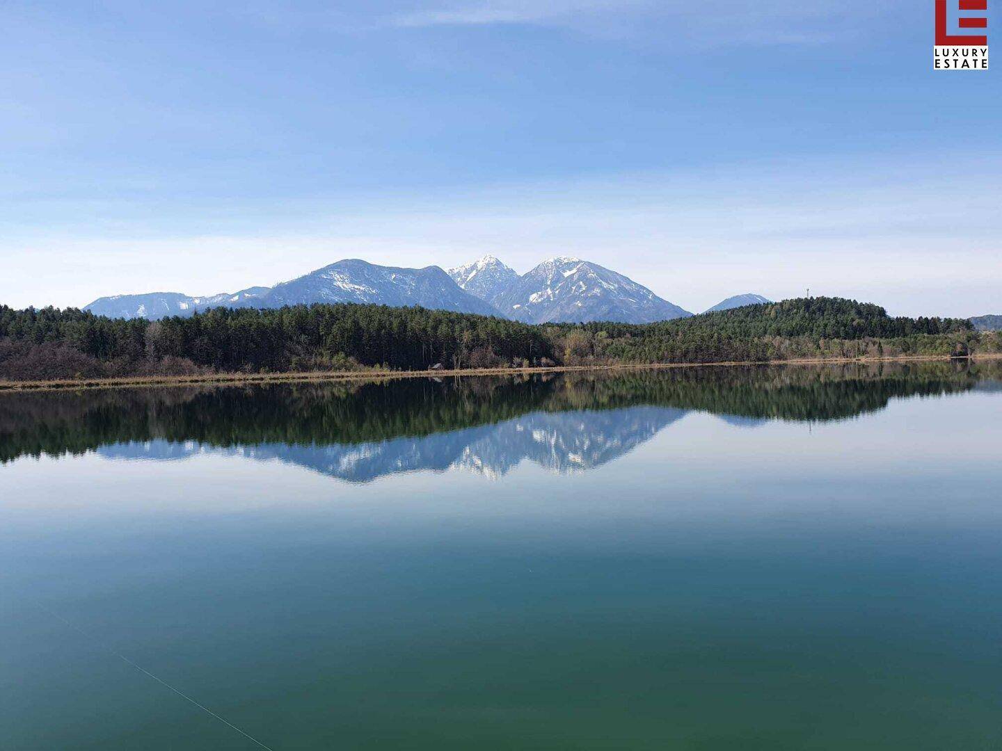Spiegelglatter See reflektiert die schneebedeckten Berge und den blauen Himmel.