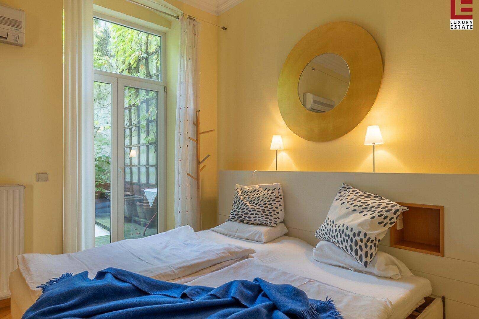 Gemütliches Schlafzimmer mit Doppelbett, großem Fenster und Blick ins Grüne.