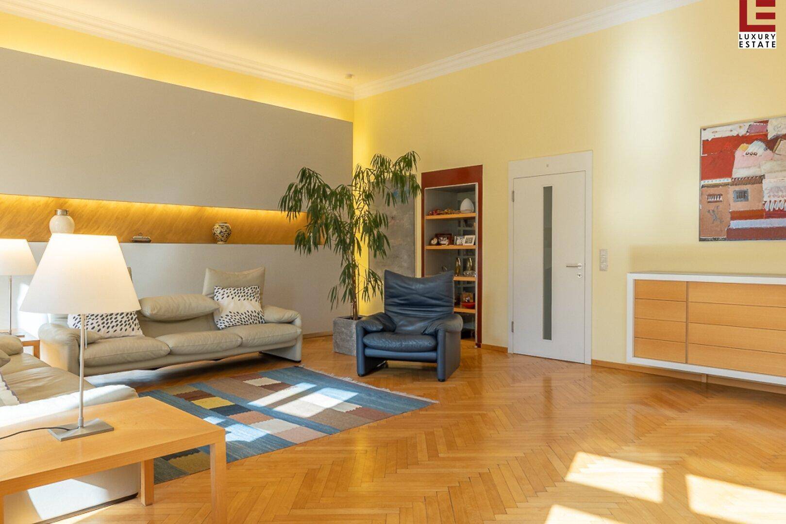 Geräumiges Wohnzimmer mit Fischgrätparkett, bequemen Sofas und farbigem Teppich.