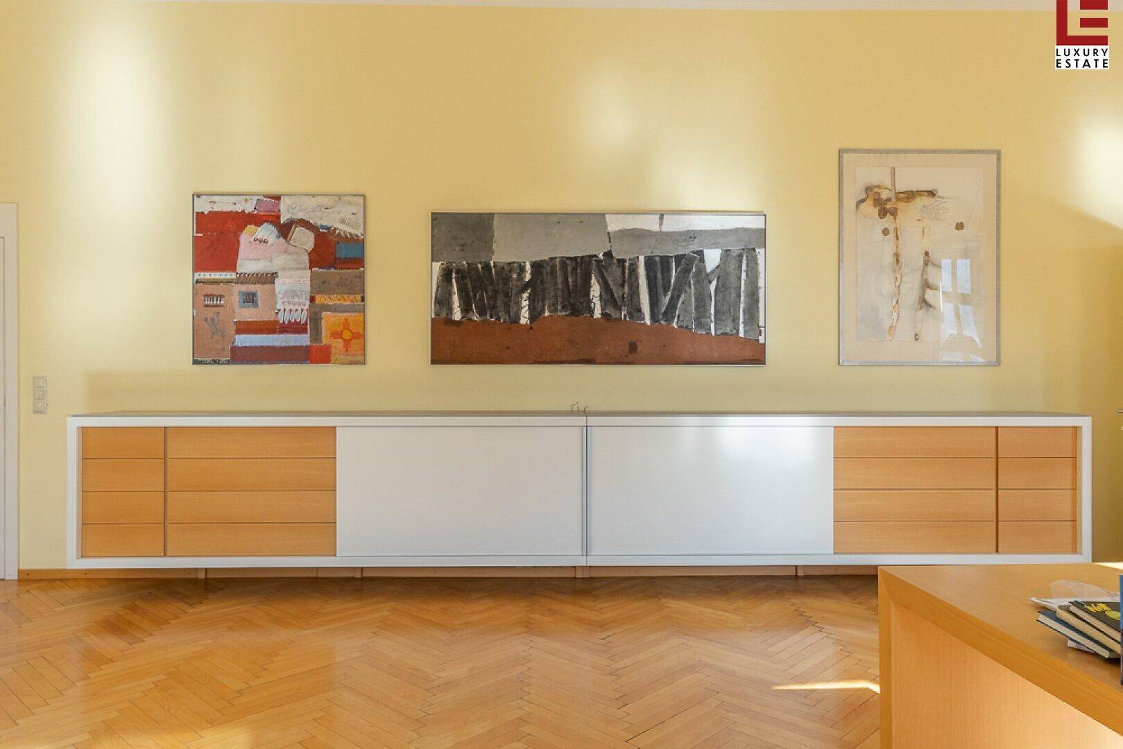 Modernes Sideboard mit Holz- und Weißfronten unter Kunstwerken im Wohnbereich.