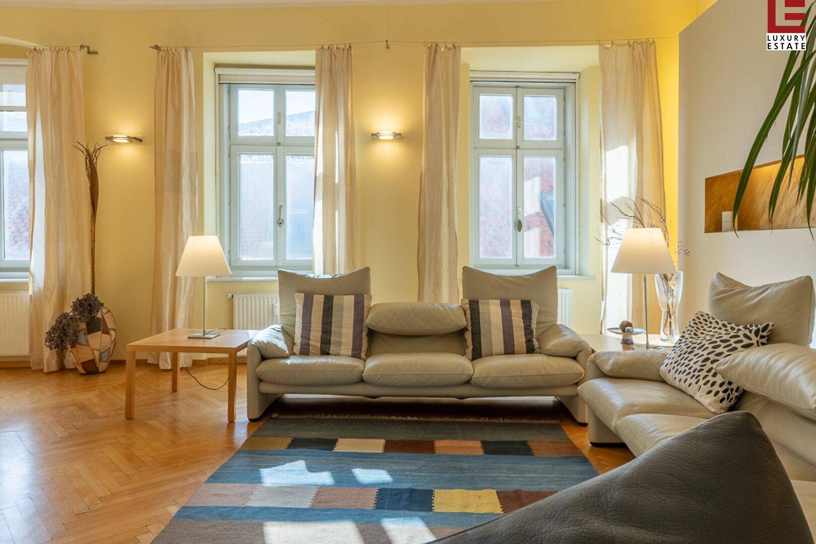 Helles Wohnzimmer mit bequemen Sofas, großzügigen Fenstern und Parkettboden.