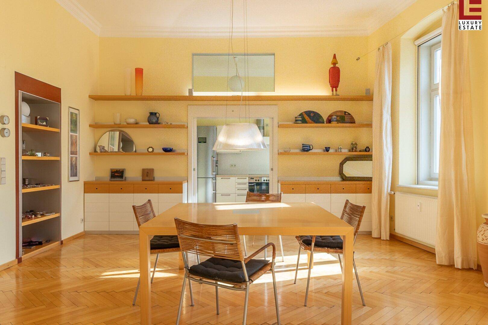 Heller Essbereich mit Holztisch, Fischgrätparkett und Zugang zur Küche.