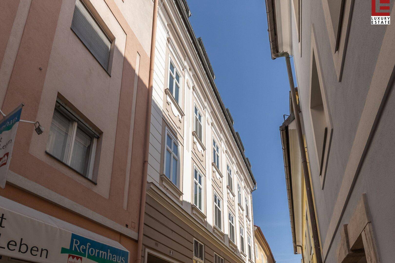 Historische Fassade eines Gebäudes in einer engen Gasse, unter blauem Himmel.
