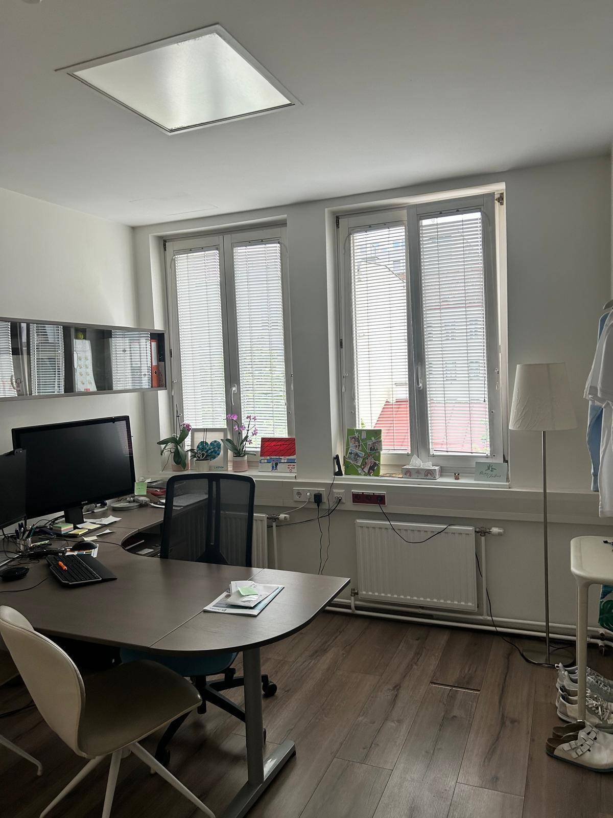 Einzelbüro mit einem Schreibtisch, Computer und Jalousien an den Fenstern für Privatsphäre.