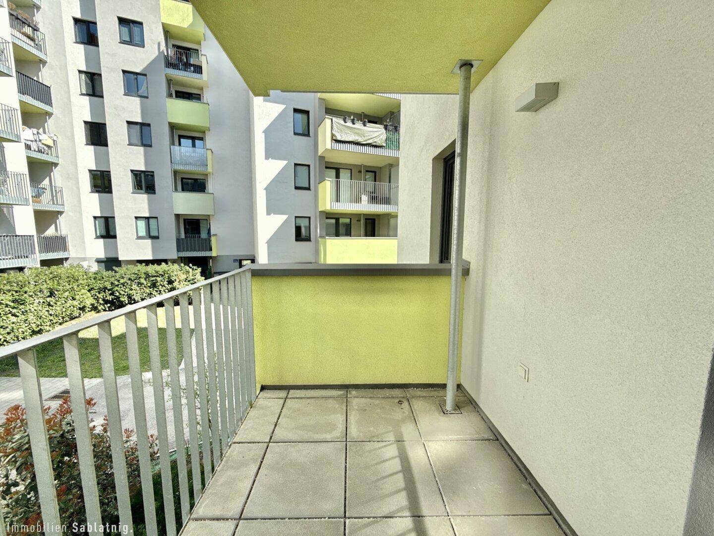 Geräumiger Balkon mit Fliesenboden und Blick auf die umliegenden Wohngebäude.