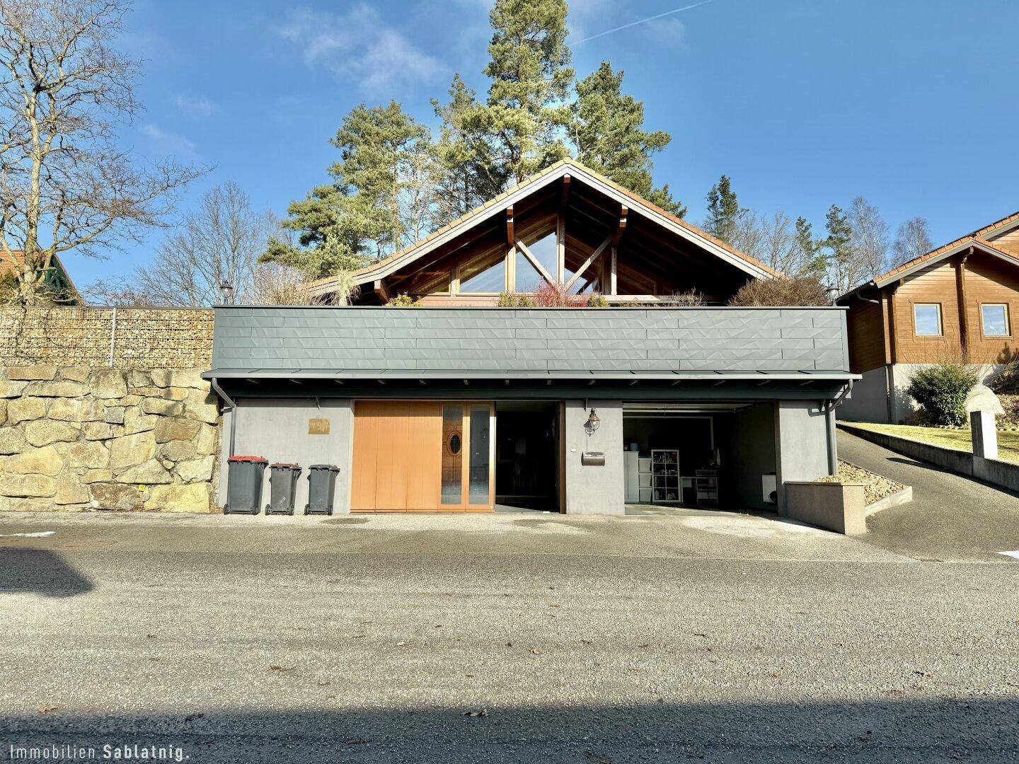 Attraktives Holzhaus mit integrierter Garage und modernem Design in grüner Umgebung.