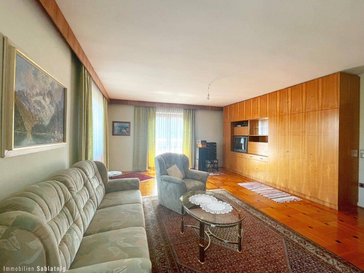 Gemütliches Wohnzimmer mit Sofa, Teppich und großen Holzschränken.