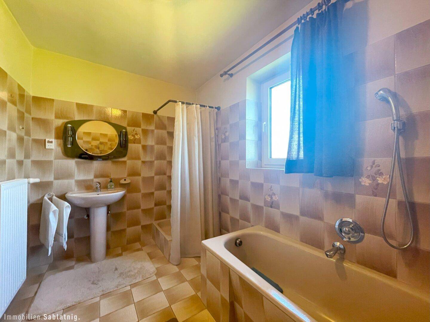 Helles Badezimmer mit Badewanne, Duschvorhang und Fenster.