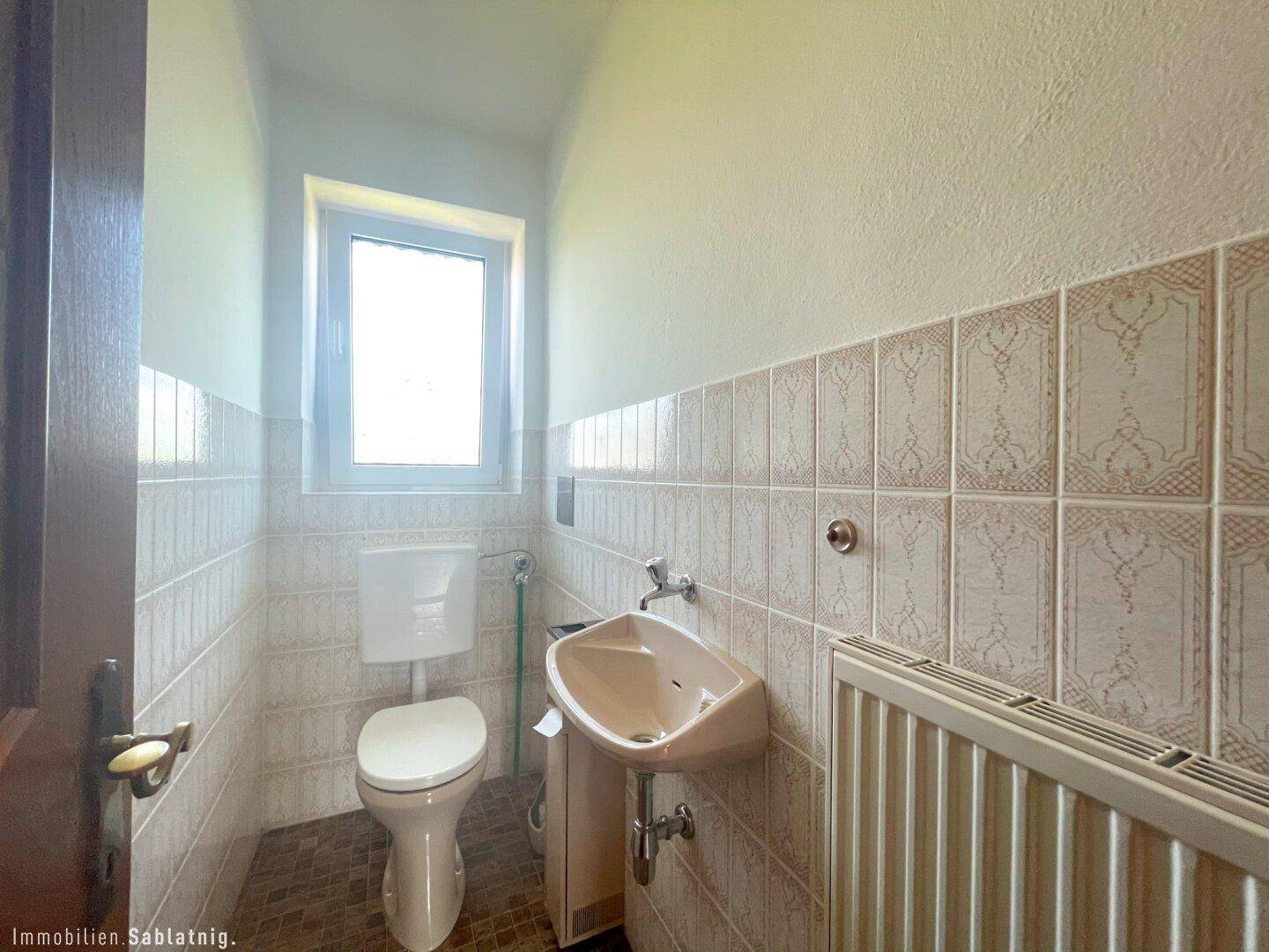 Kleines Gäste-WC mit Fenster, WC und Waschbecken.